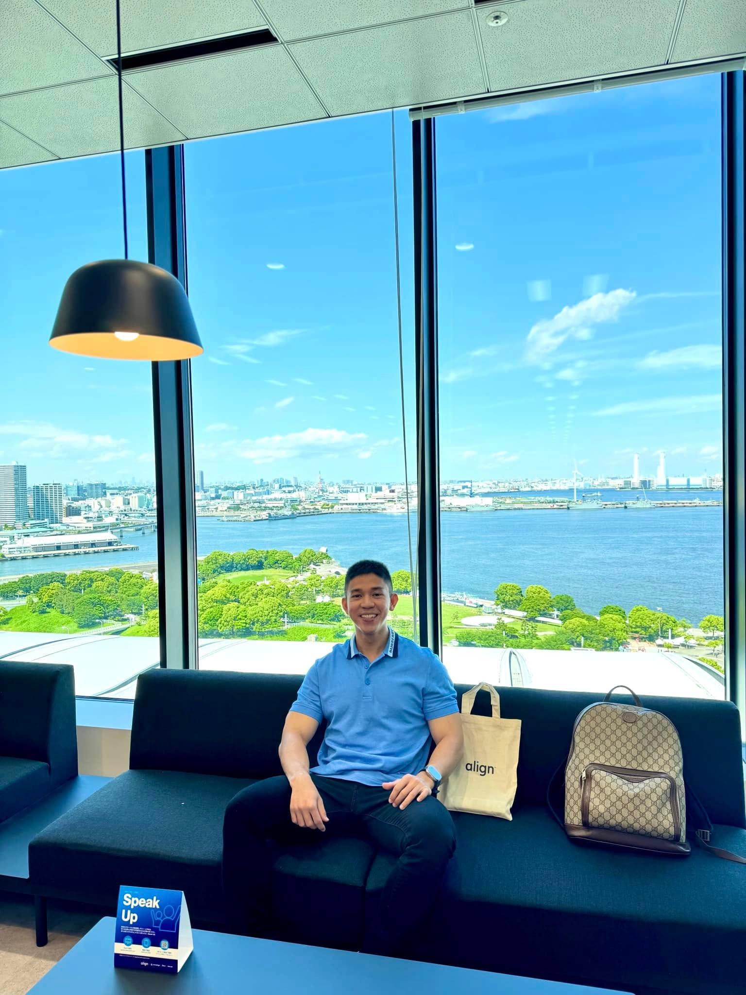 Bác sĩ Hồ Lê Bảo Ân ngồi tại khu chờ của văn phòng Align Technology, phía sau là khung cửa kính nhìn ra khu vực cảng.