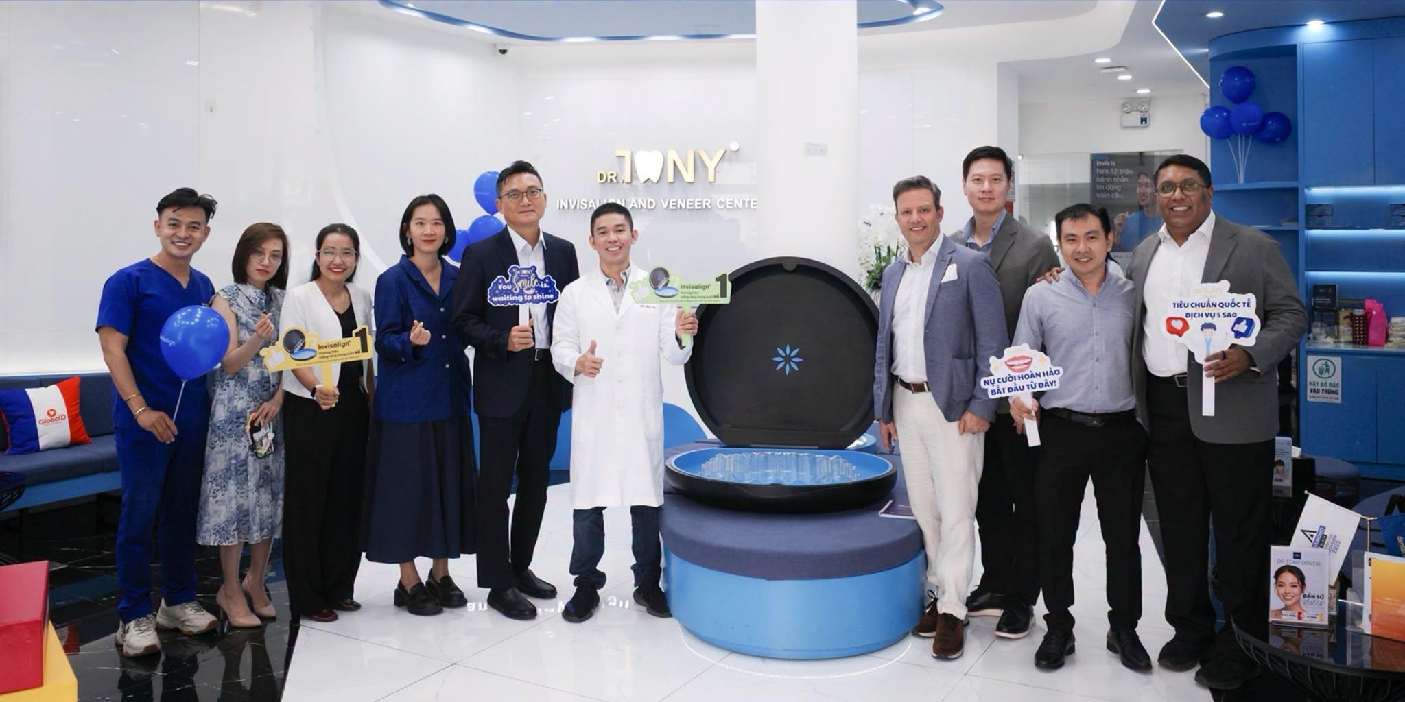 Phái đoàn Align Technology và đội ngũ Dr Tony Dental chụp chung tại sảnh phòng khám, phía sau là bảng hiệu “DR. TONY — Invisalign and Veneer Center”.