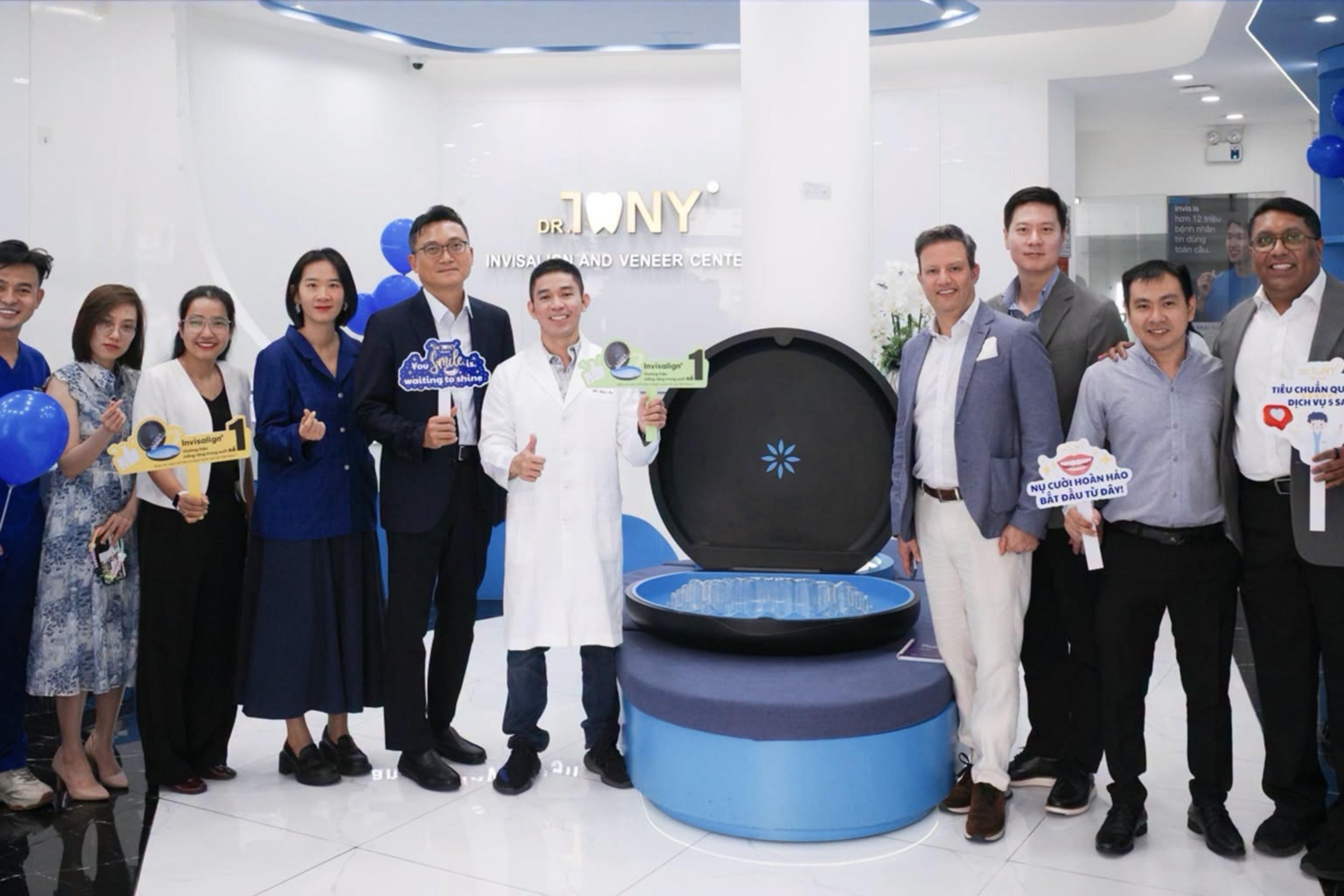 Phái đoàn Align Technology và đội ngũ Dr Tony Dental chụp chung tại sảnh phòng khám, phía sau là bảng hiệu “DR. TONY — Invisalign and Veneer Center”.