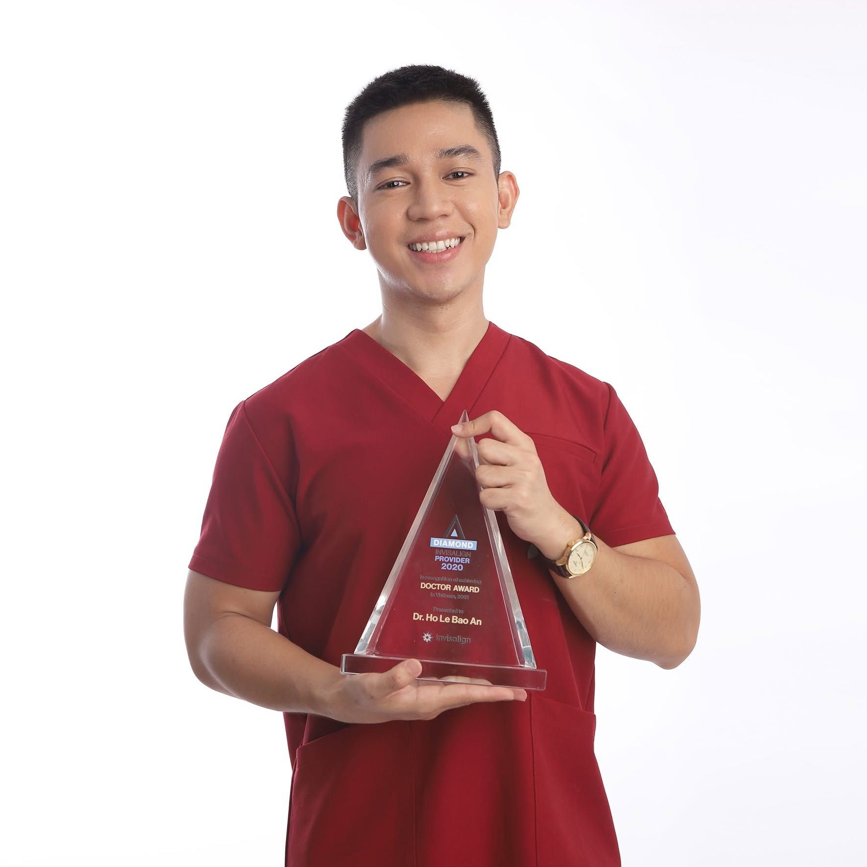 Dr Ho Le Bao An holding the Invisalign Diamond Provider glass trophy, engraved Doctor Award in Vietnam, 2021