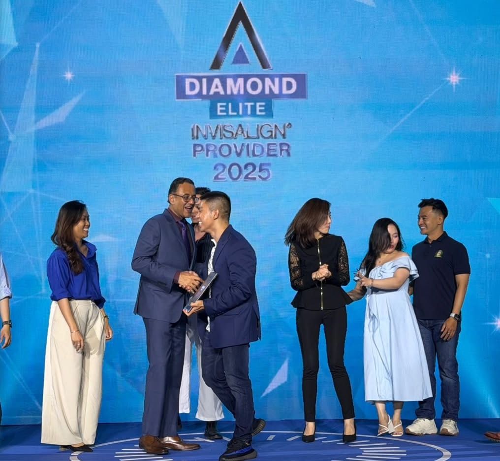 Đại diện Align Technology bắt tay và trao bảng chứng nhận cho Bác sĩ Hồ Lê Bảo Ân trên sân khấu, màn hình phía sau ghi “Diamond Elite Invisalign Provider 2025”.