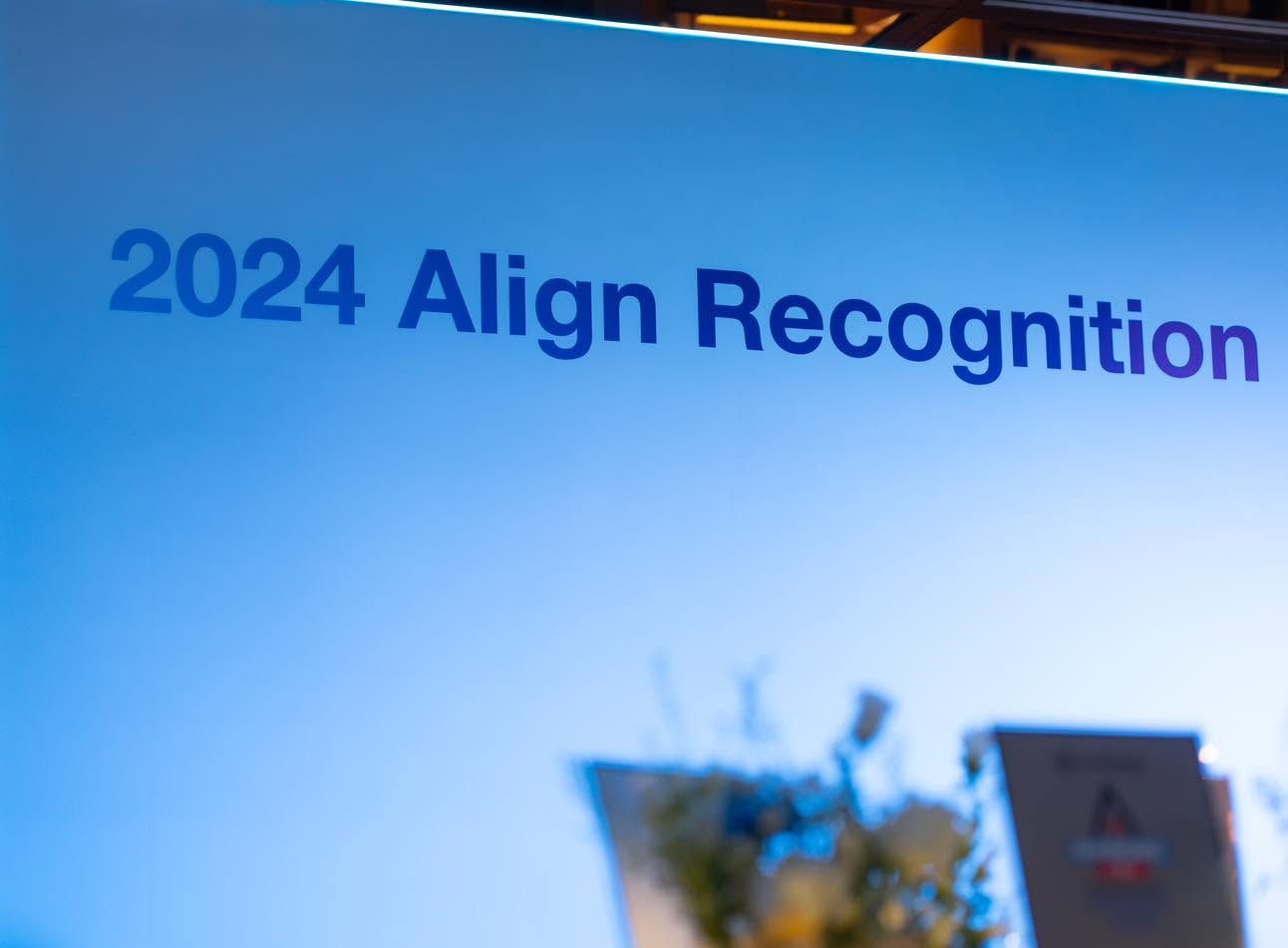 Cận cảnh phông nền sự kiện ghi “2024 Align Recognition” trên nền chuyển sắc xanh.