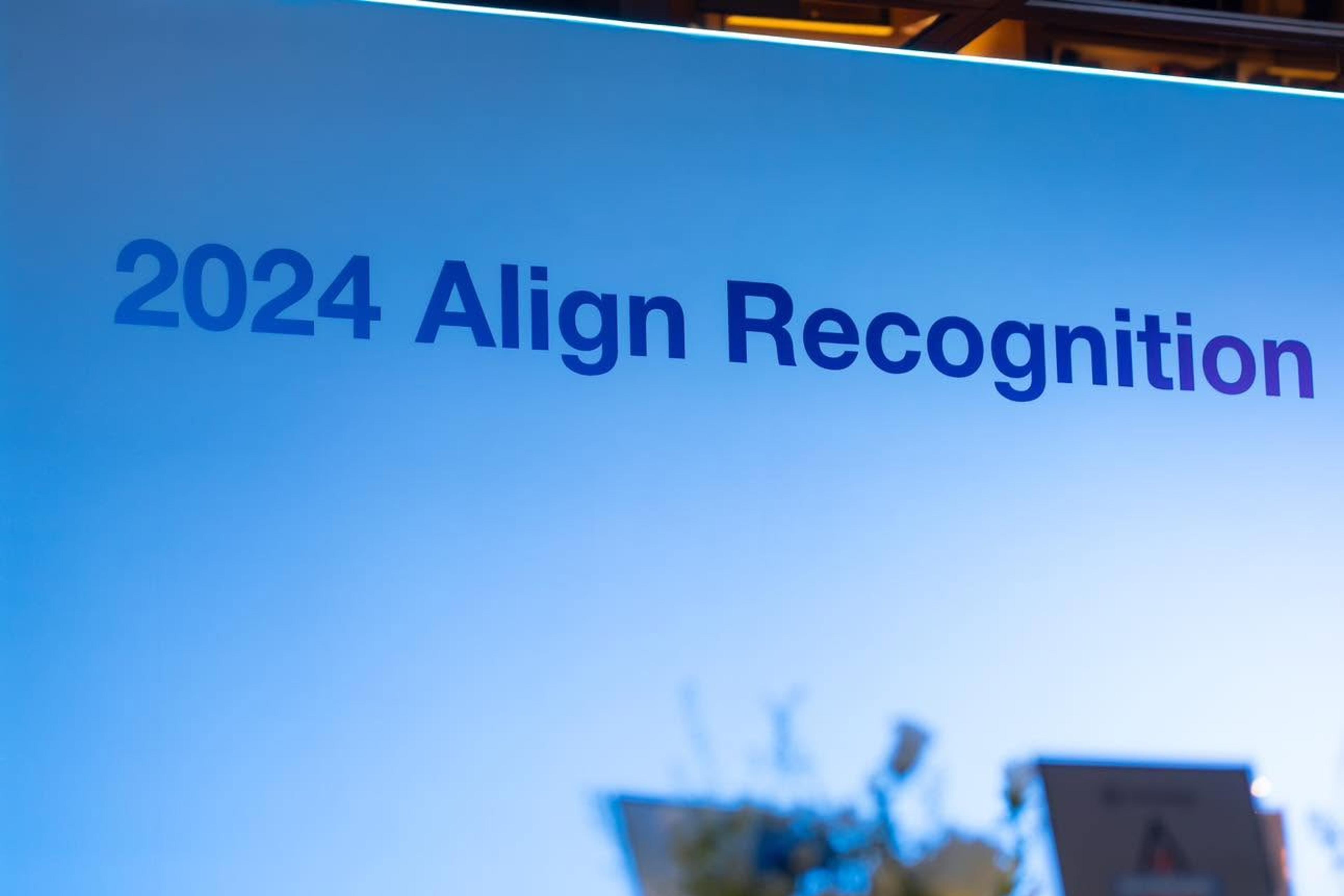 Cận cảnh phông nền sự kiện ghi “2024 Align Recognition” trên nền chuyển sắc xanh.