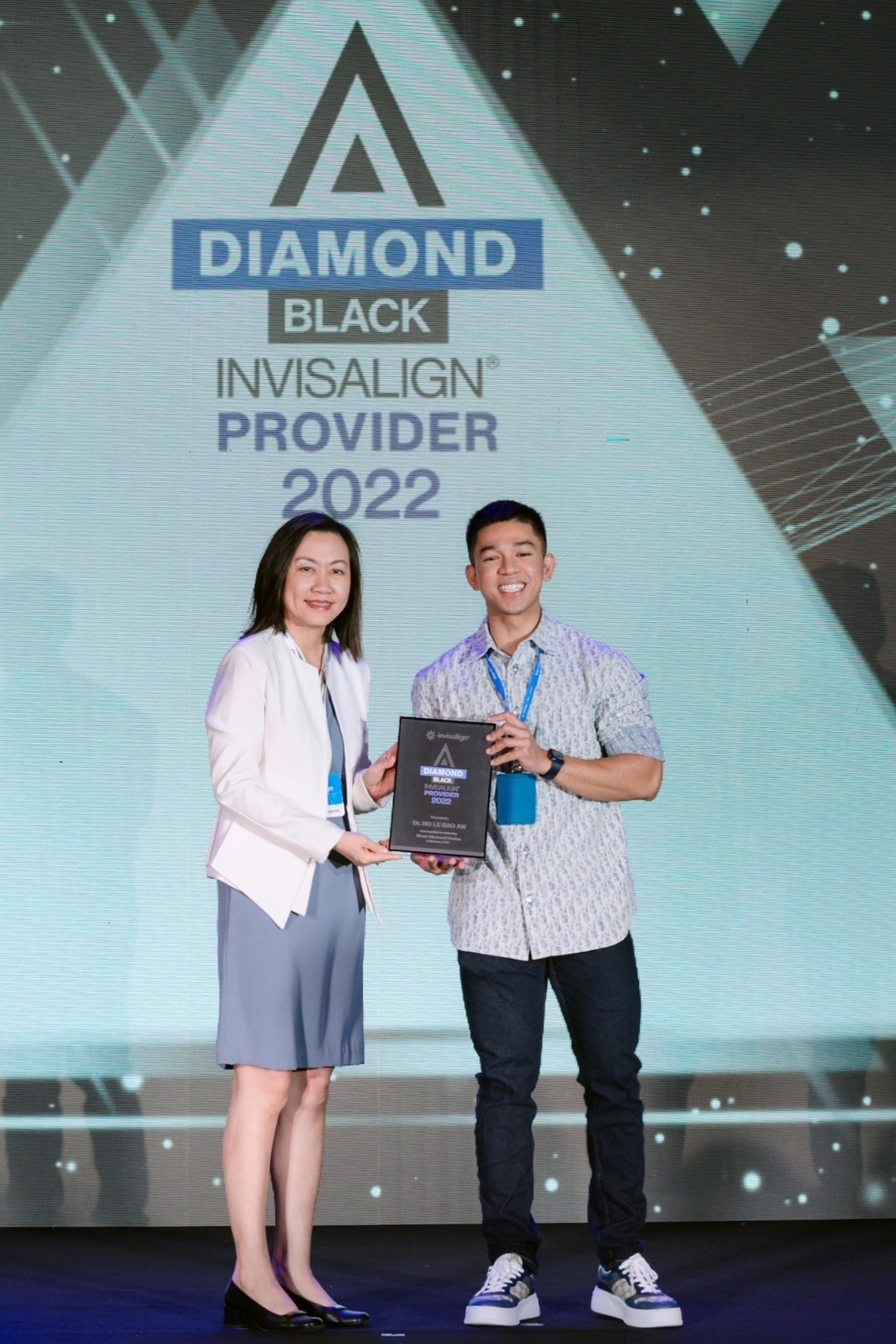 Dr Ho Le Bao An receiving the Invisalign Black Diamond plaque on stage, 2022