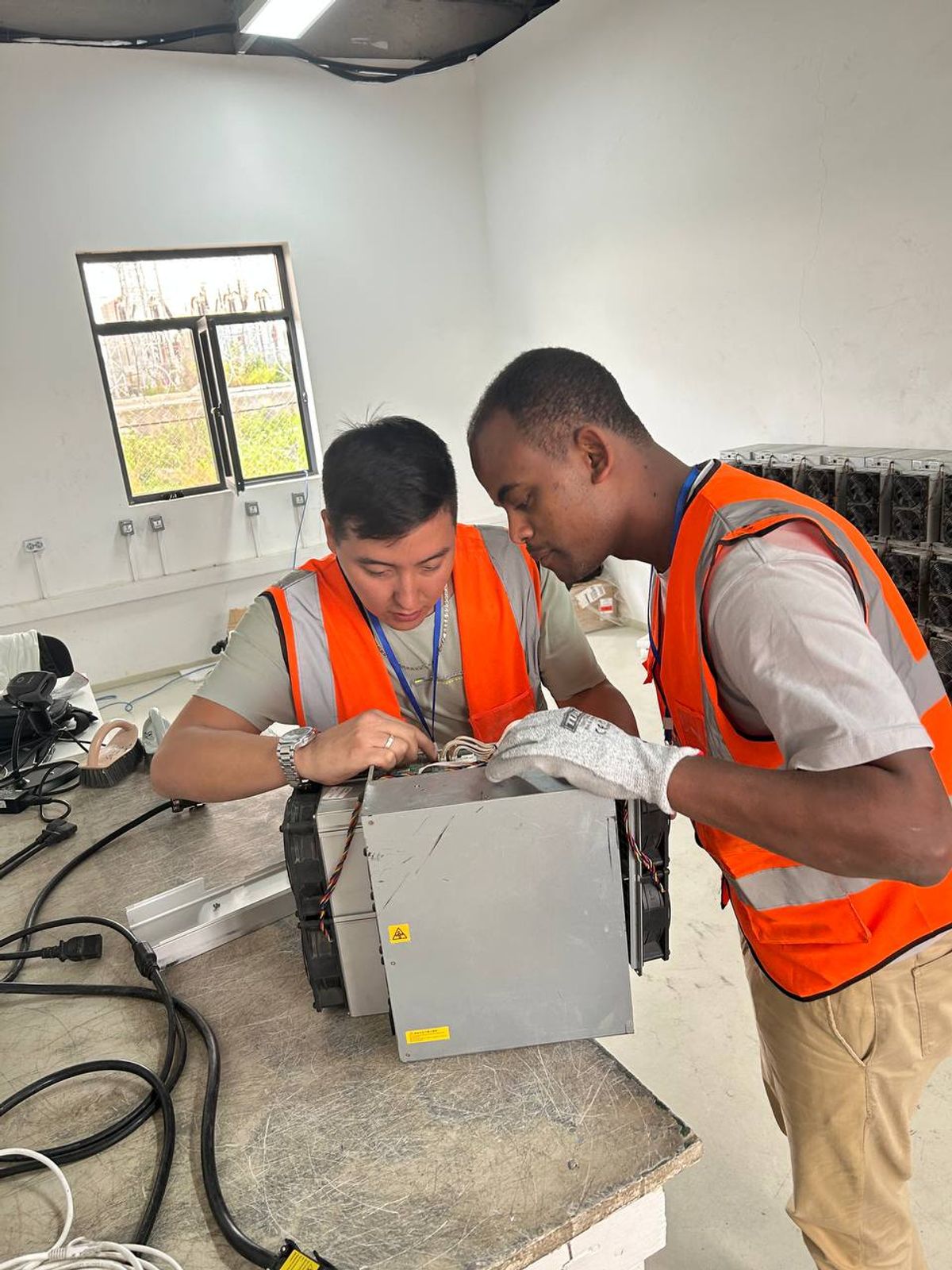 Technicians examining an ASIC miner at a repair facility