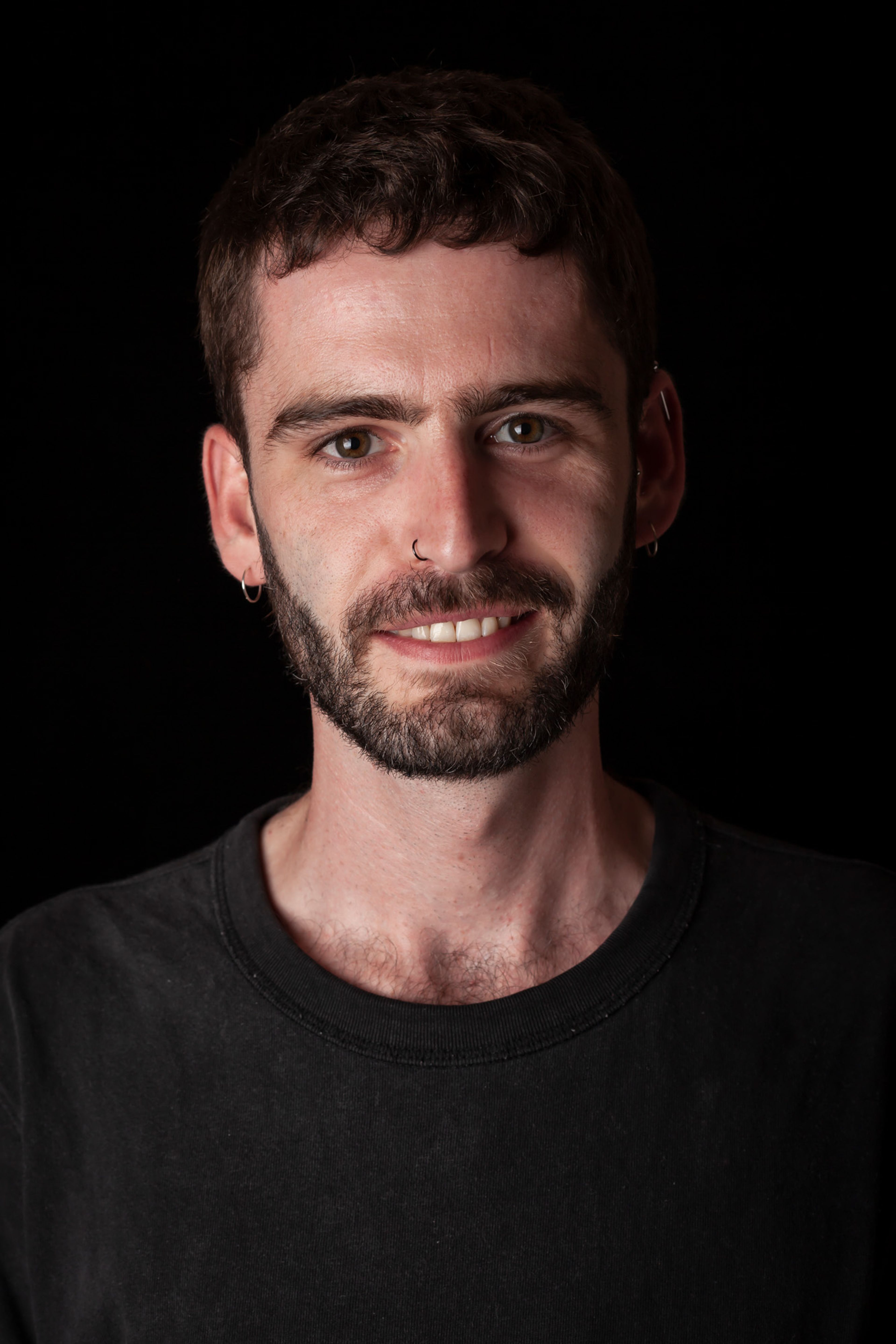 Portrait of a man with short dark hair, a beard, dressed in a black shirt