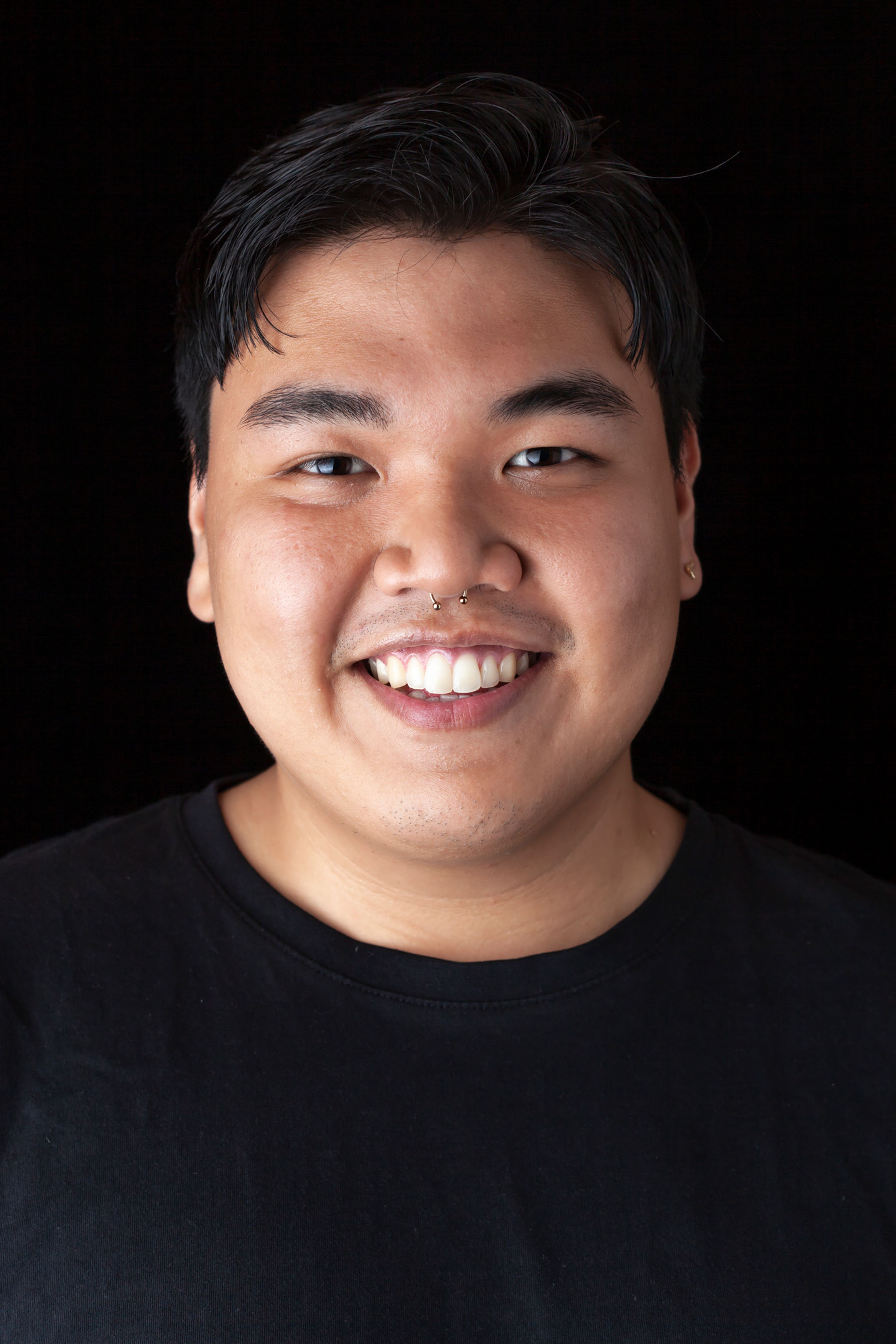 A portrait of a person with a warm smile, wearing a black shirt