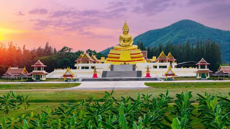 A giant golden Buddha at a temple complex below the hills near Hua Hin at sunset