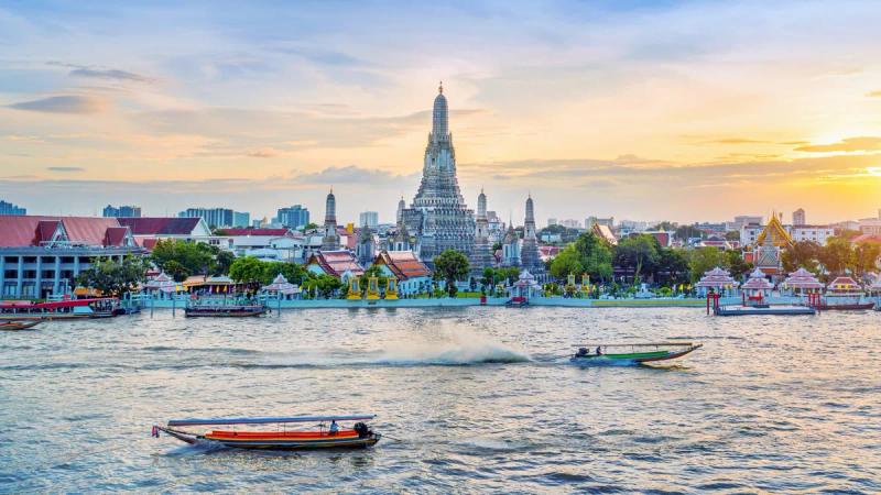 Longtail boats on the Chao Phraya river in front of Wat Arun at sunset