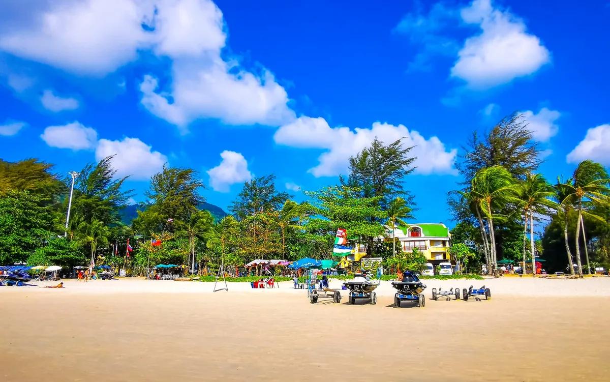 Palm-fringed white sand beach with jet skis and beach umbrellas in Phuket