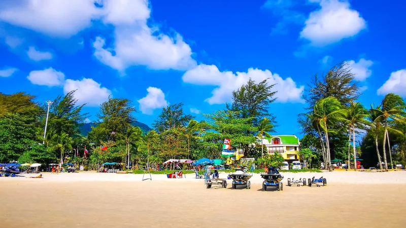 Palm-fringed white sand beach with jet skis and beach umbrellas in Phuket