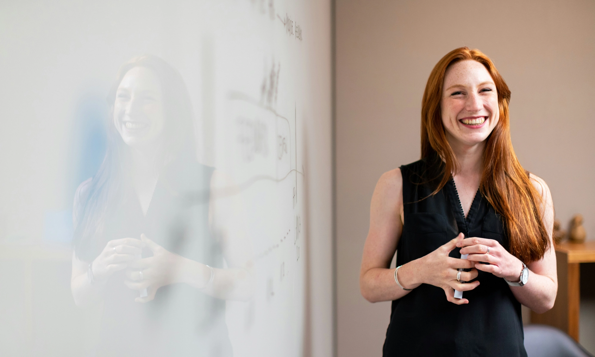 Woman standing at a whiteboard, engaged in change management.