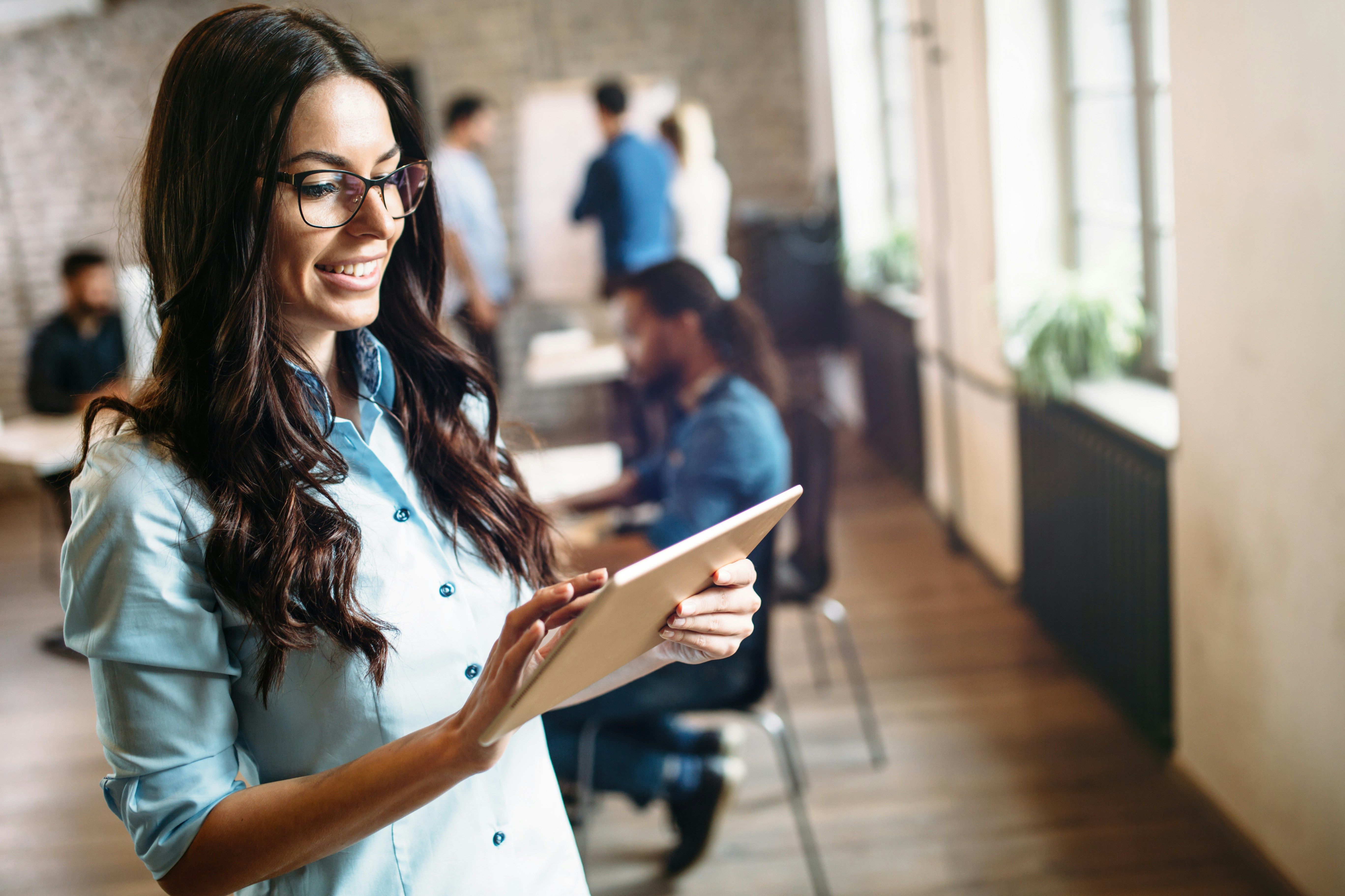Frau mit blauer Bluse und Tablet in der Hand im Büro