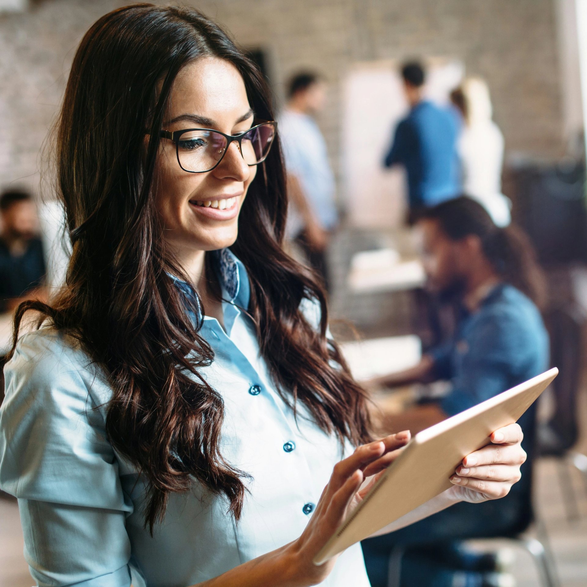 Woman wearing a blue blouse and holding a tablet in the office