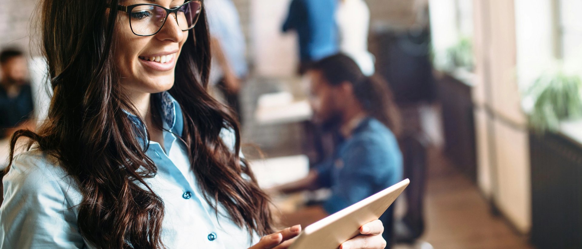 Frau mit blauer Bluse und Tablet im Büro