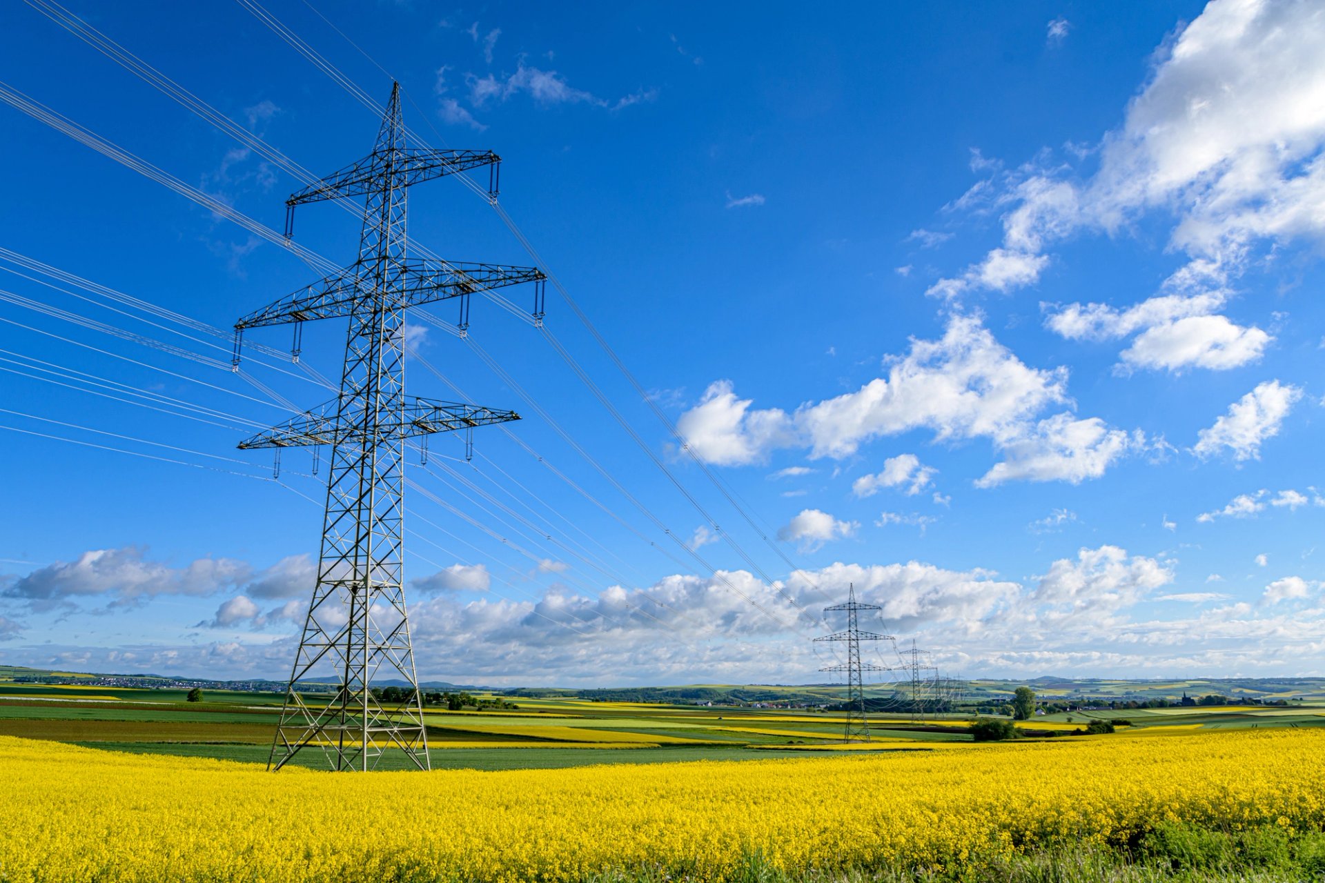 Frau steht am Meer und hält ein orangenes Tuch vor sich.
