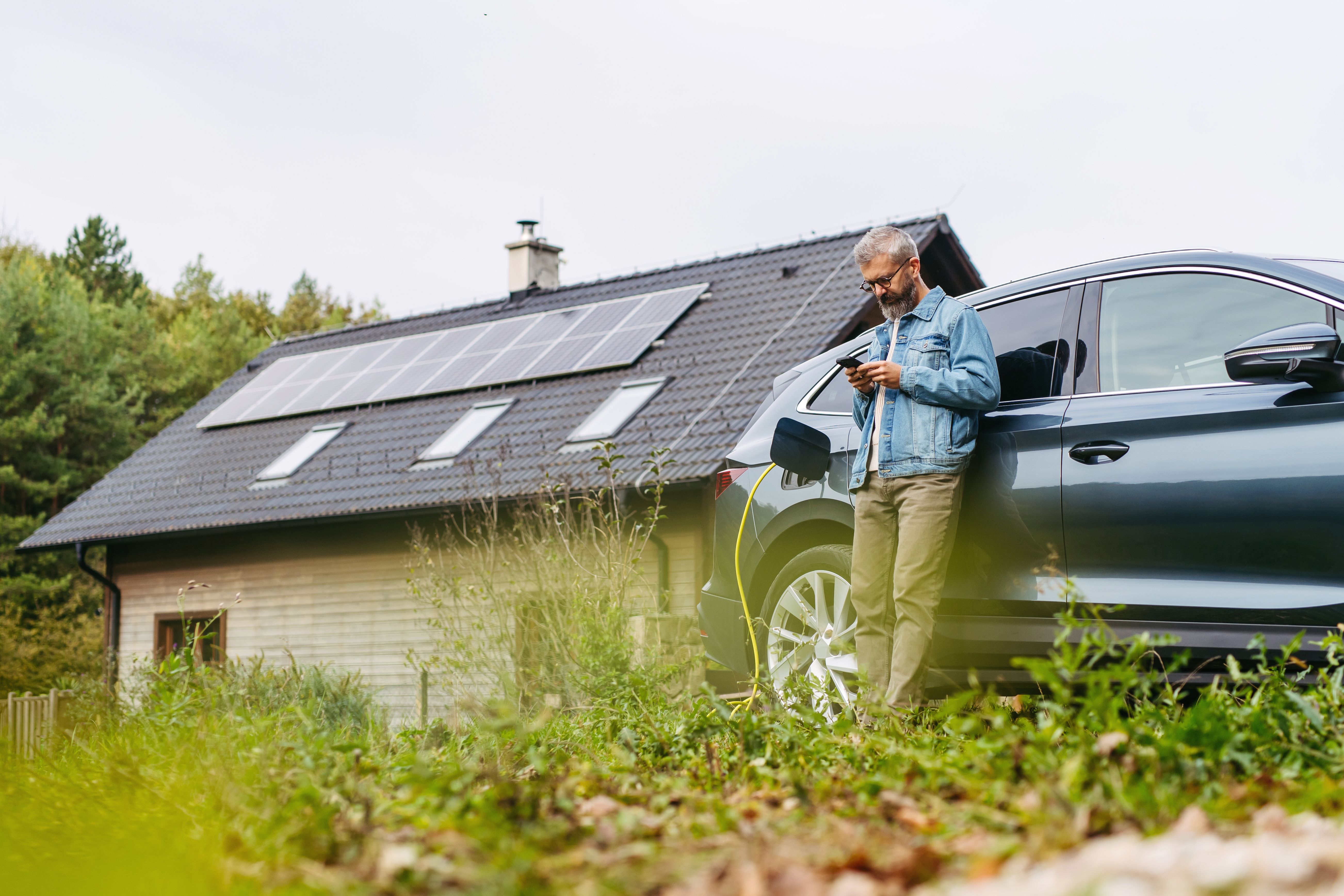 A man charges his electric car outside his home using solar power from the roof.