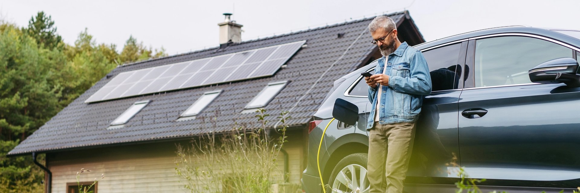 A man charges his electric car outside his home using solar power from the roof.
