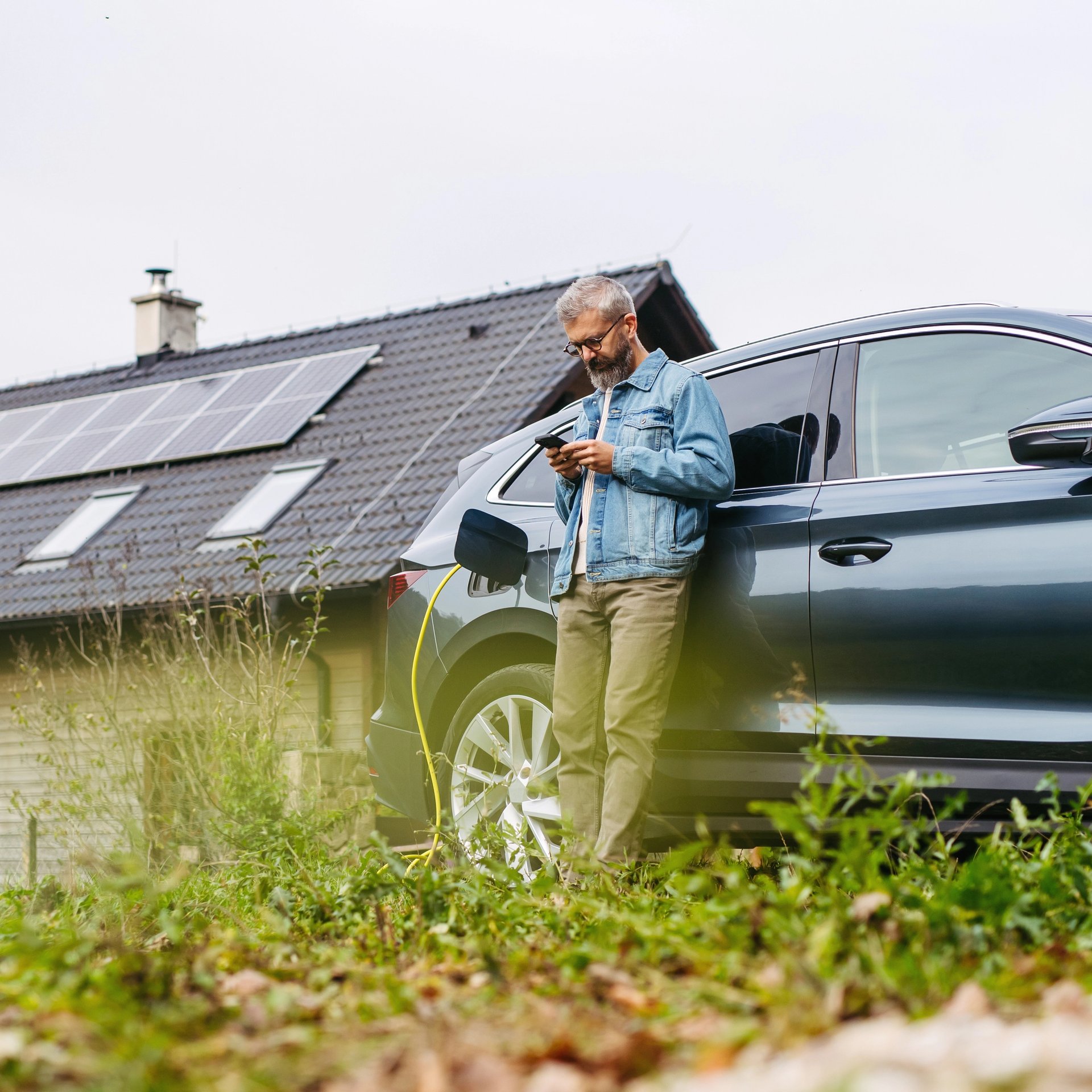 A man charges his electric car outside his home using solar power from the roof.