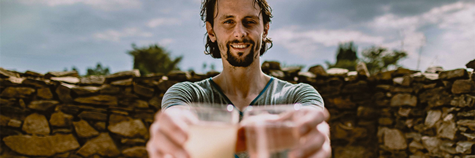 A man, Neven Subotic, holds two glasses of water out in front of him with his arms outstretched.