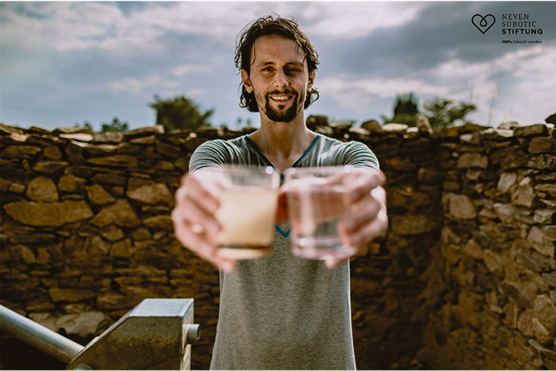 Ein Mann, Neven Subotic, hält mit ausgestreckten Armen zwei Gläser Wasser nach vorne.