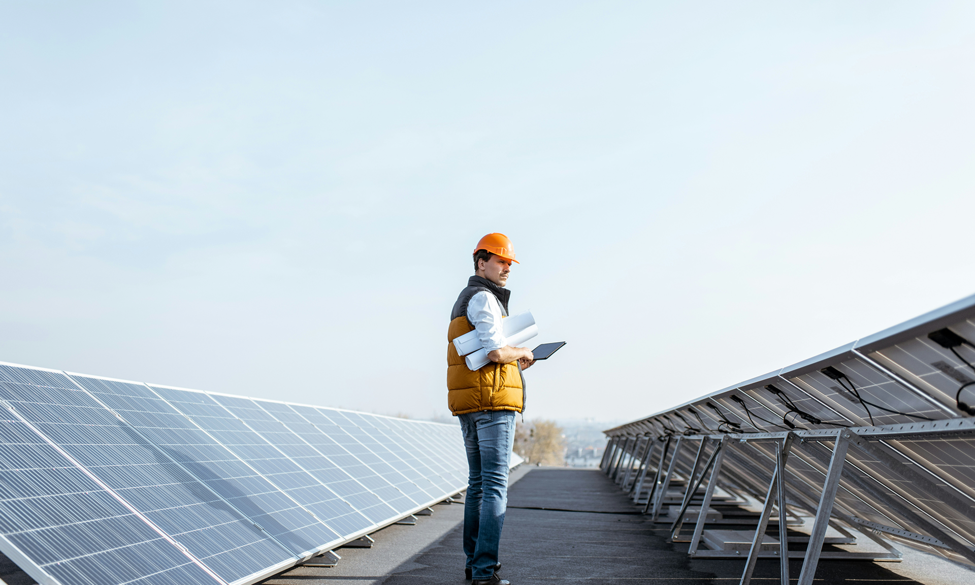 Engineer standing between solar panels with tablet and Salesforce Agentforce Energy & Utilities and rolled-up plans.