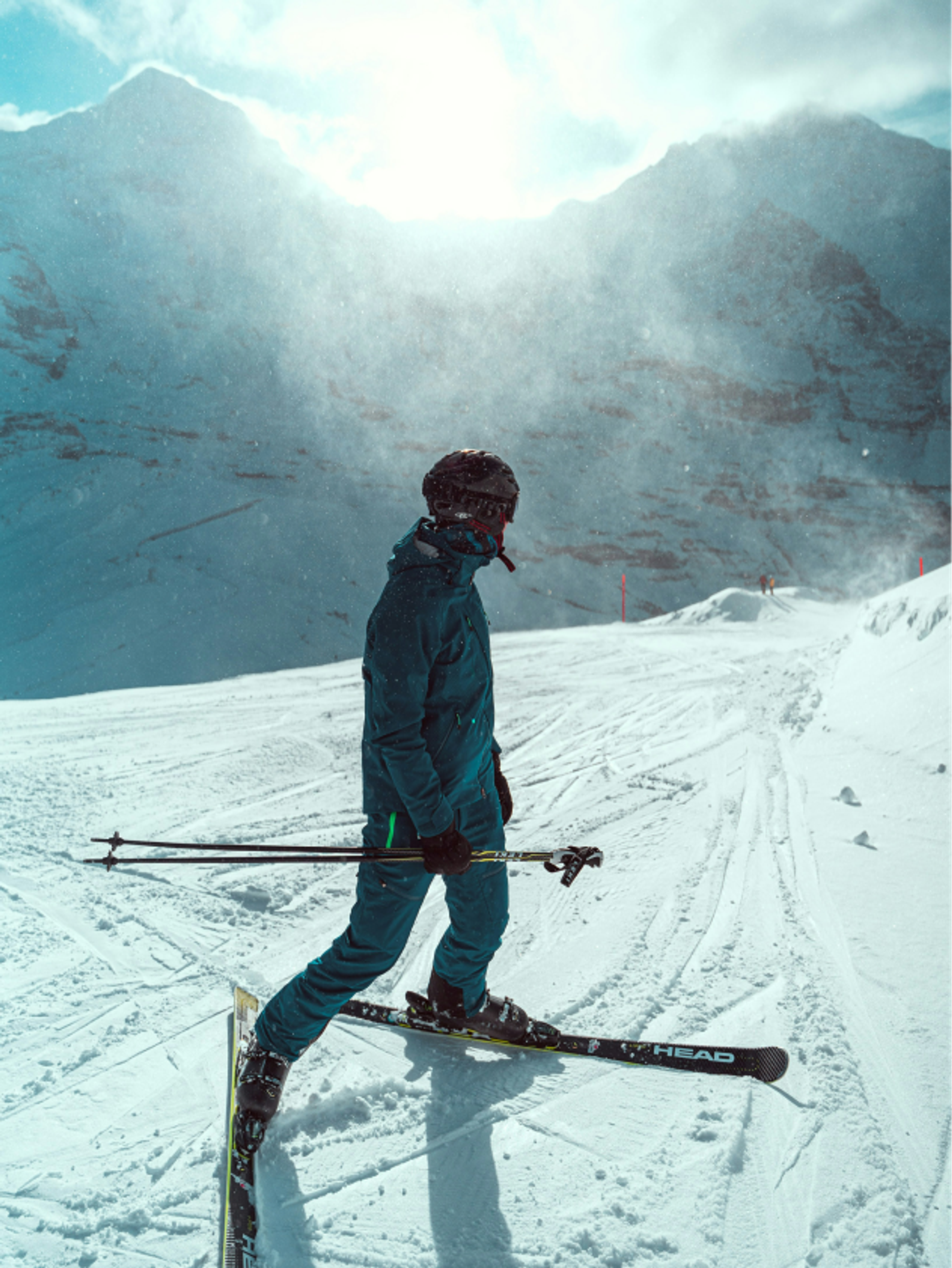 Ski-Fahrer steht auf der Piste und schaut hinter sich in die Berge.