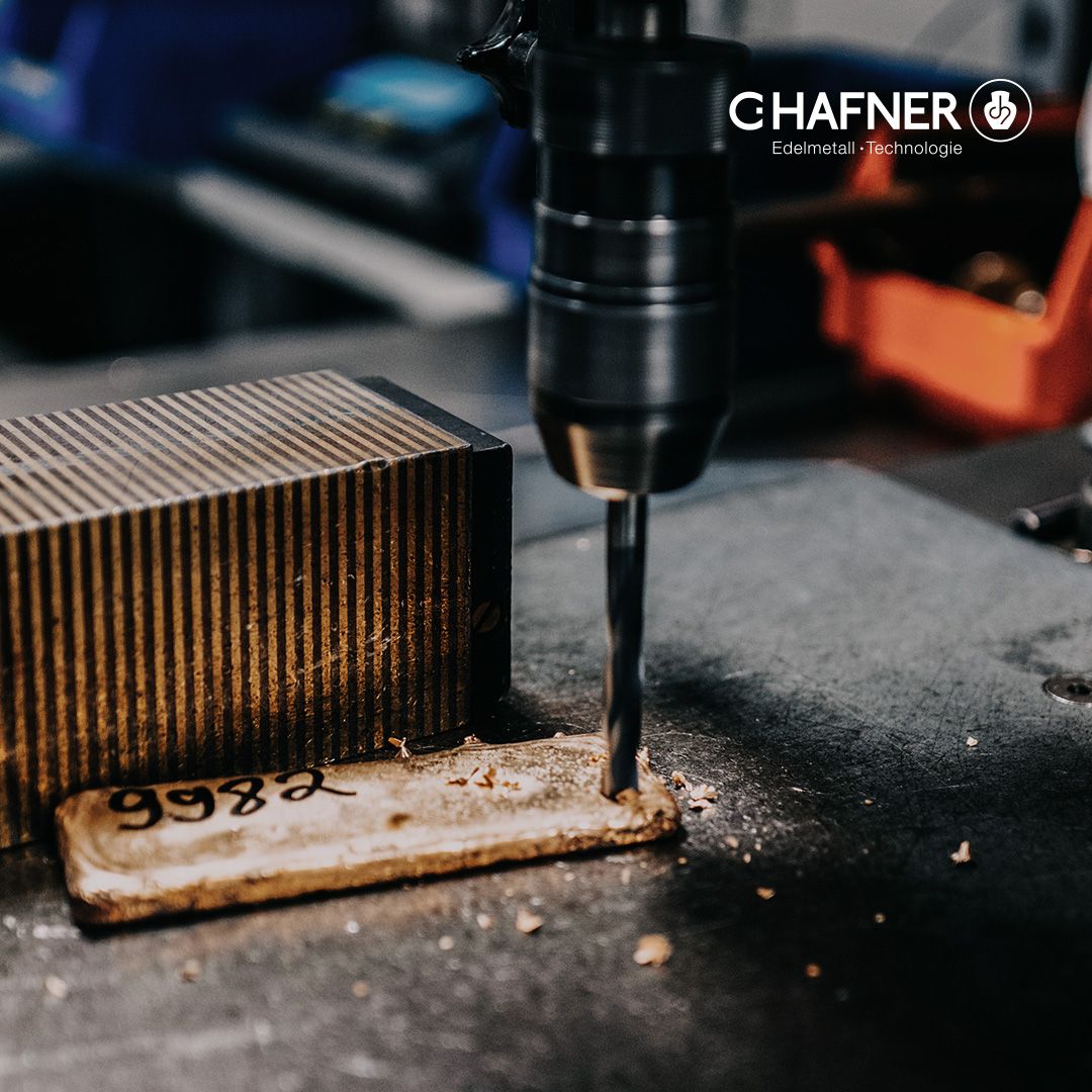 Bohrmaschine bohrt in Goldplättchen.