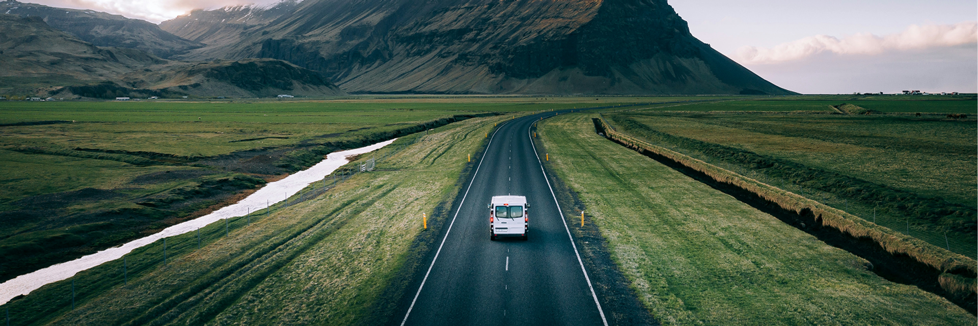 Ein weißer Sprinter fährt auf einer Landstraße auf einen Berg zu.