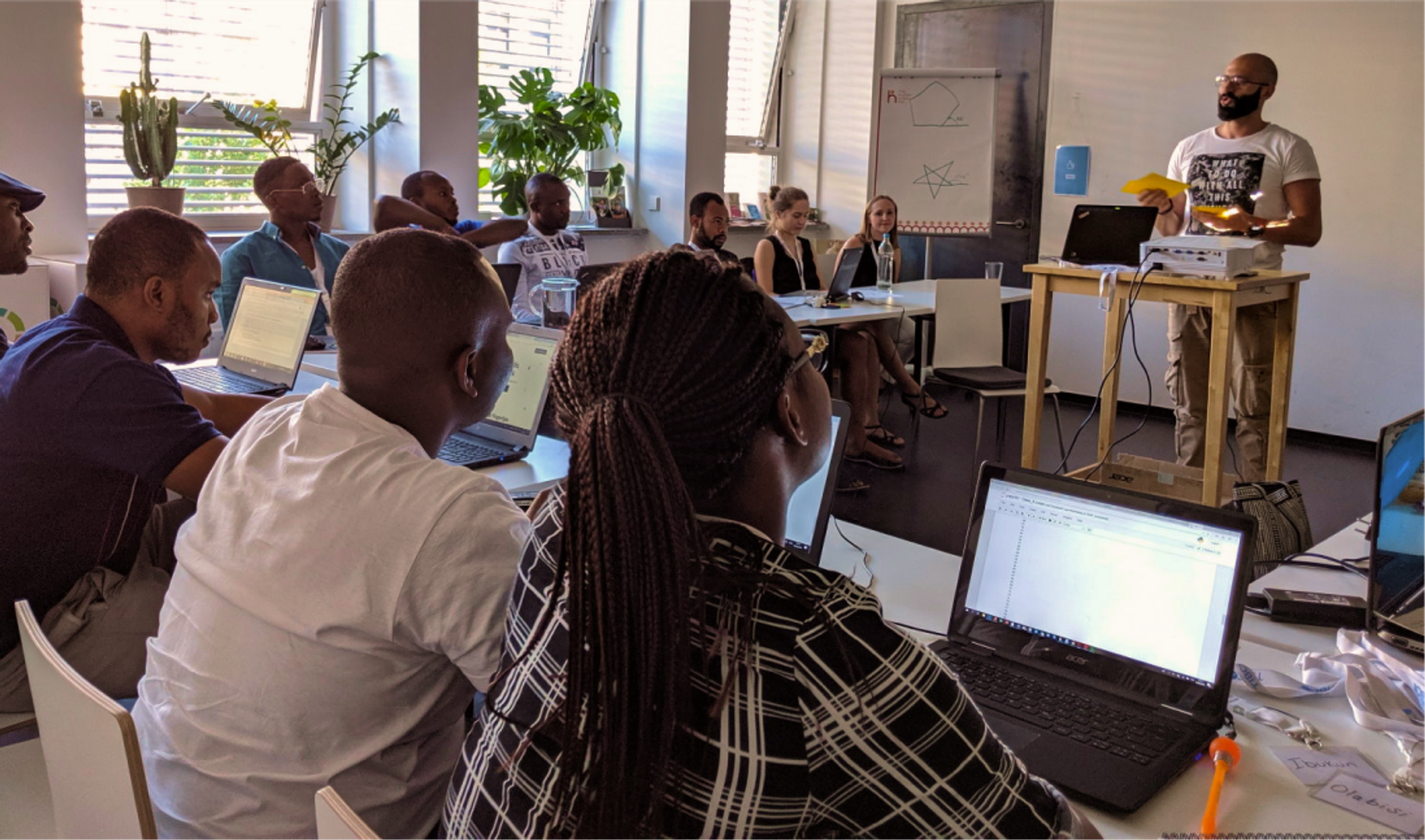 Ein Lehrer der ReDI School steht vor einer erwachsenen Klasse und unterrichtet.