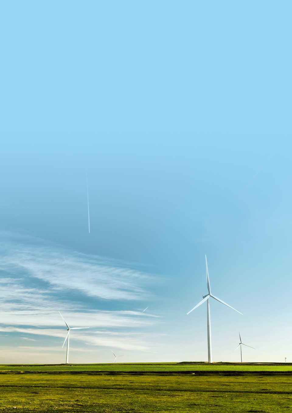 Grünes Feld mit Windrädern.