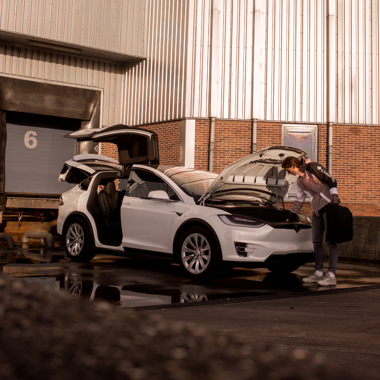 Mann beugt sich über offenen Kofferraum unter der Motorhaube.
