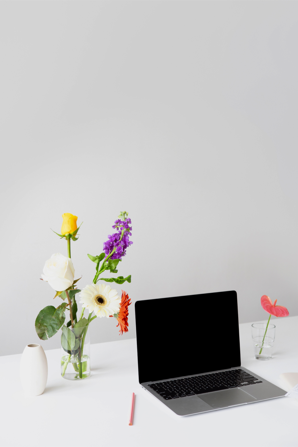Ein Laptop und daneben eine Vase mit Gerbera.