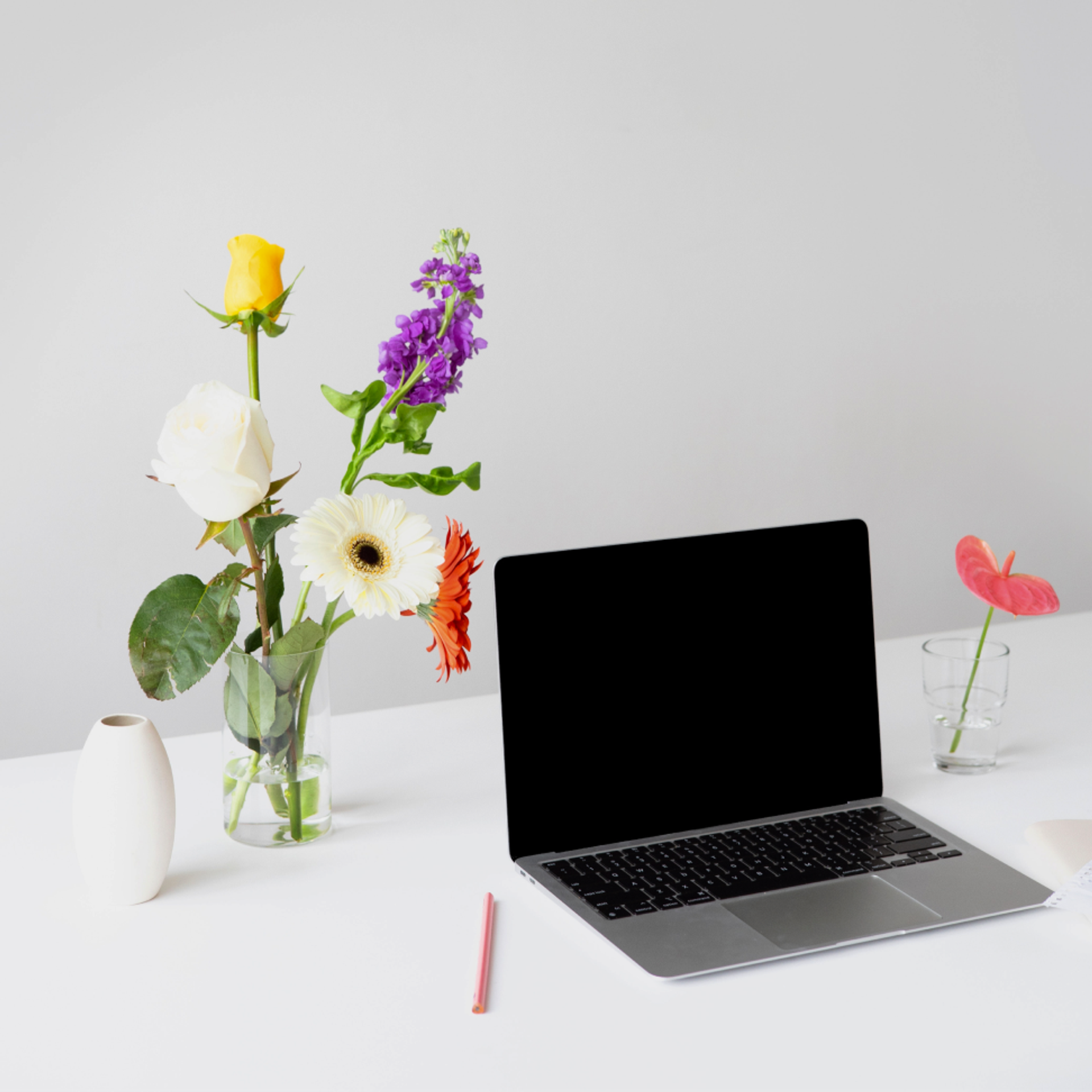 Ein Laptop und daneben eine Vase mit Gerbera.