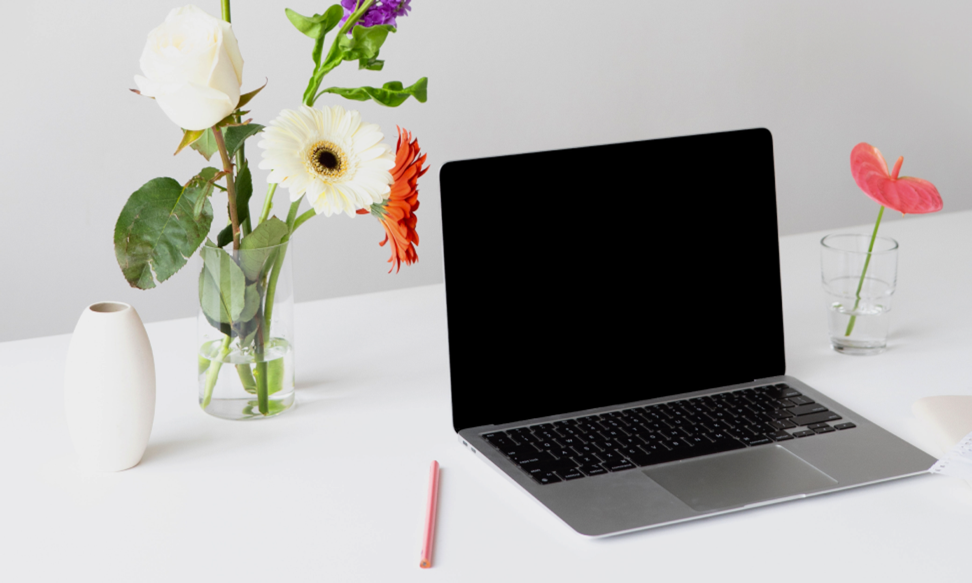 Ein Laptop und daneben eine Vase mit Gerbera.