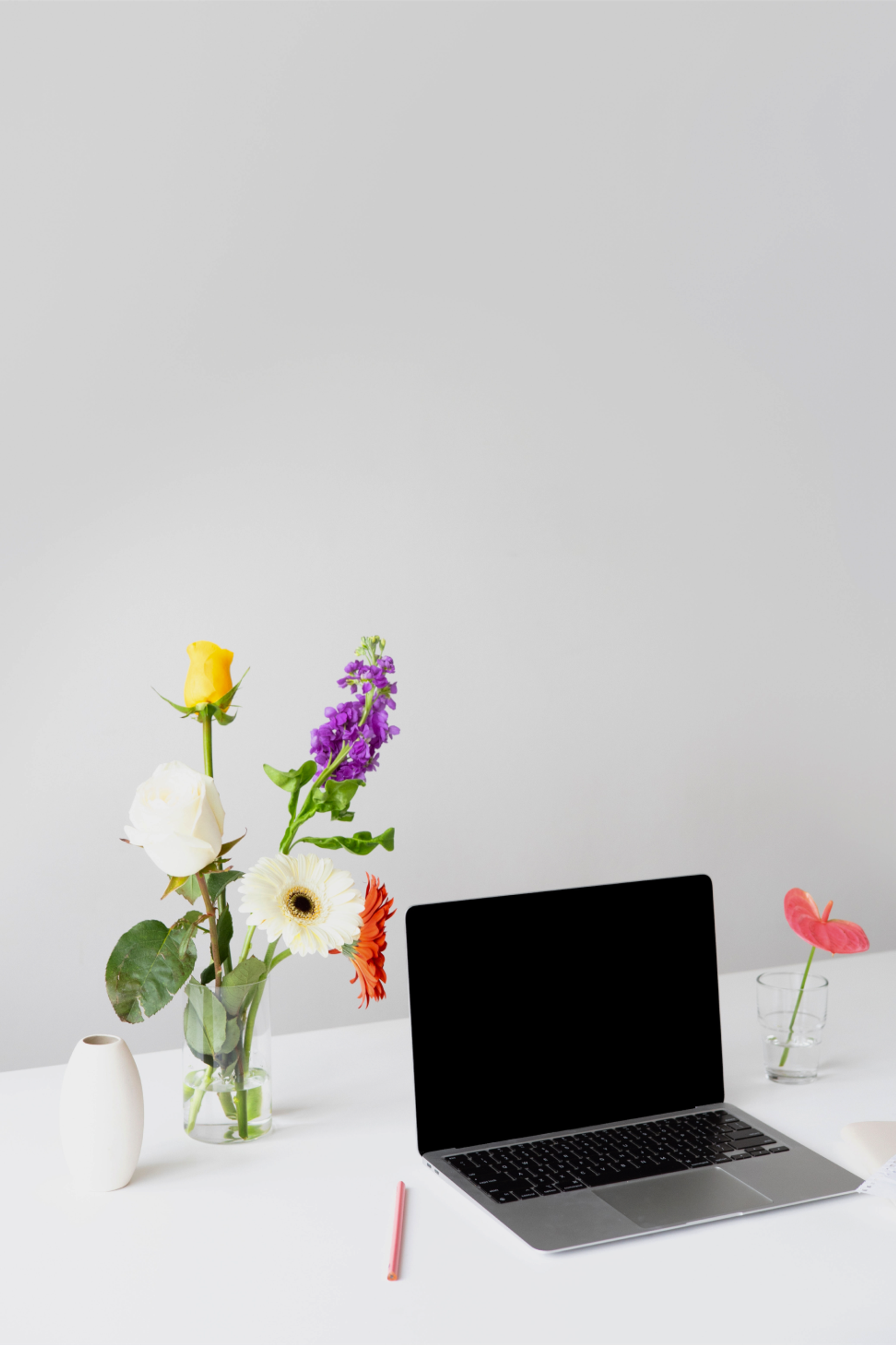 Ein Laptop und daneben eine Vase mit Gerbera.