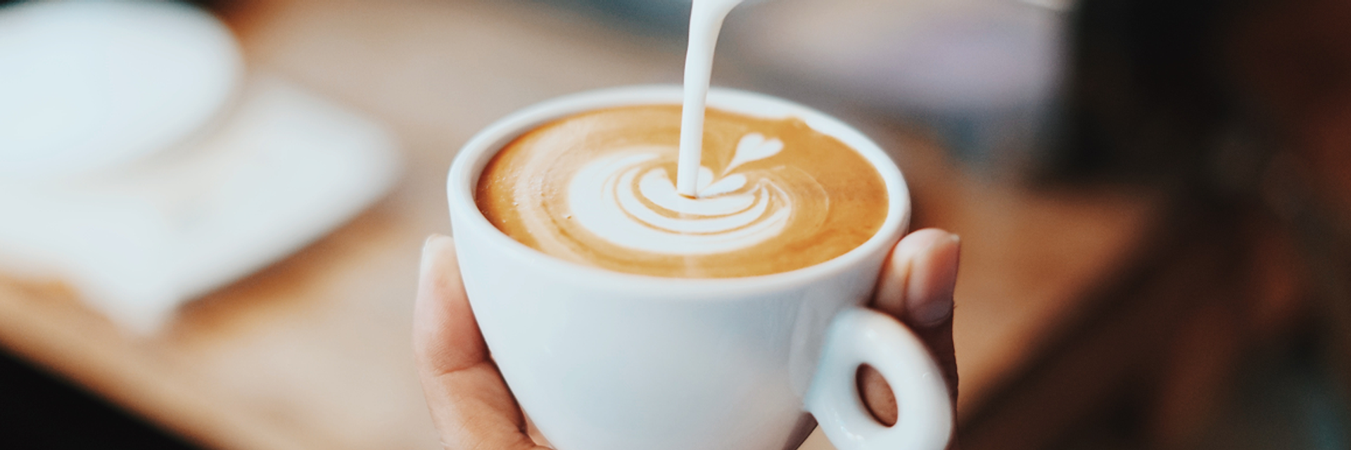 Milch wird in einen Cappuccino gegossen.