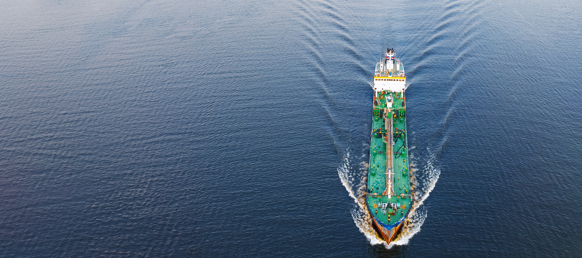 Vogelperspektive auf ein grünes Schiff auf dem Meer.