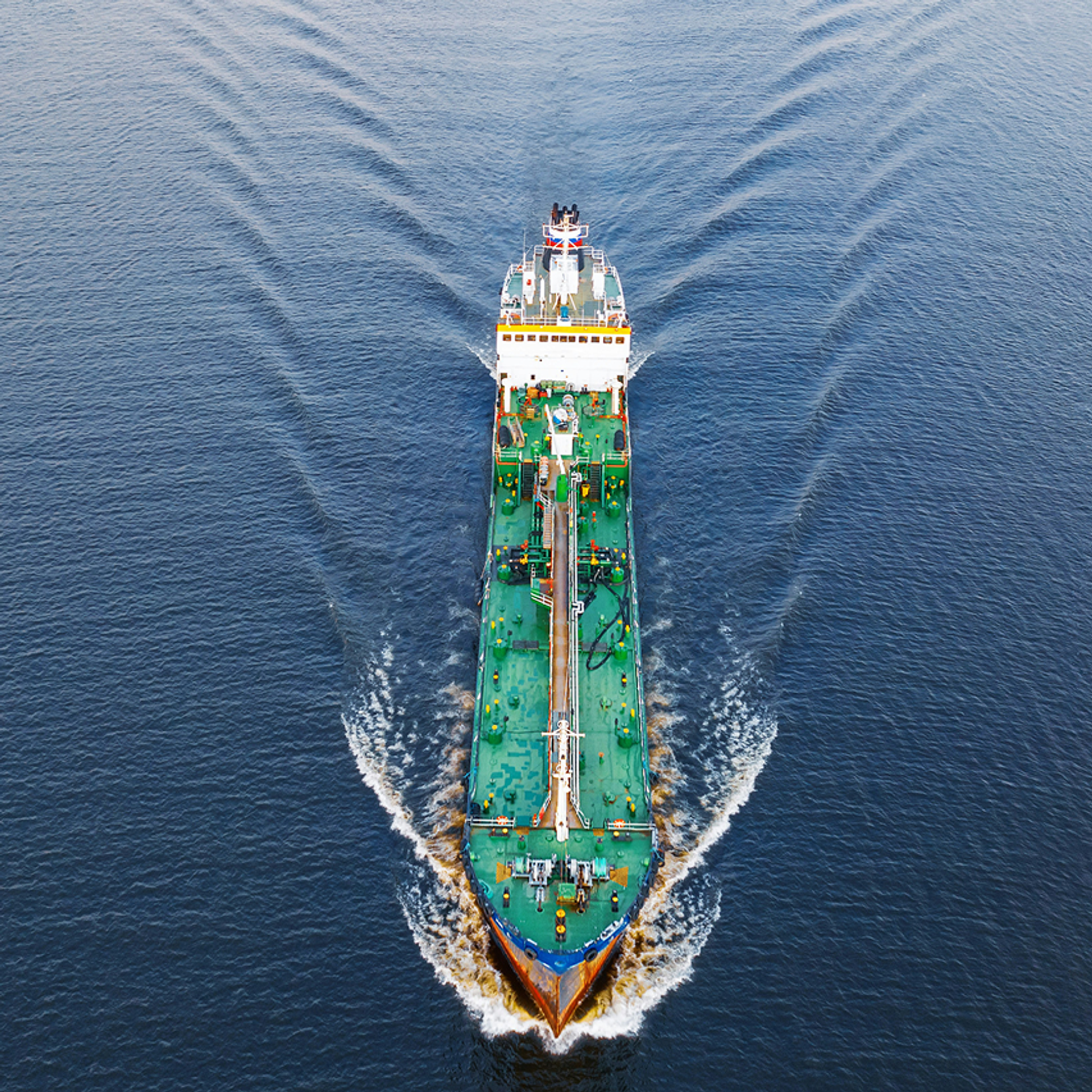 Vogelperspektive auf ein grünes Schiff auf dem Meer.