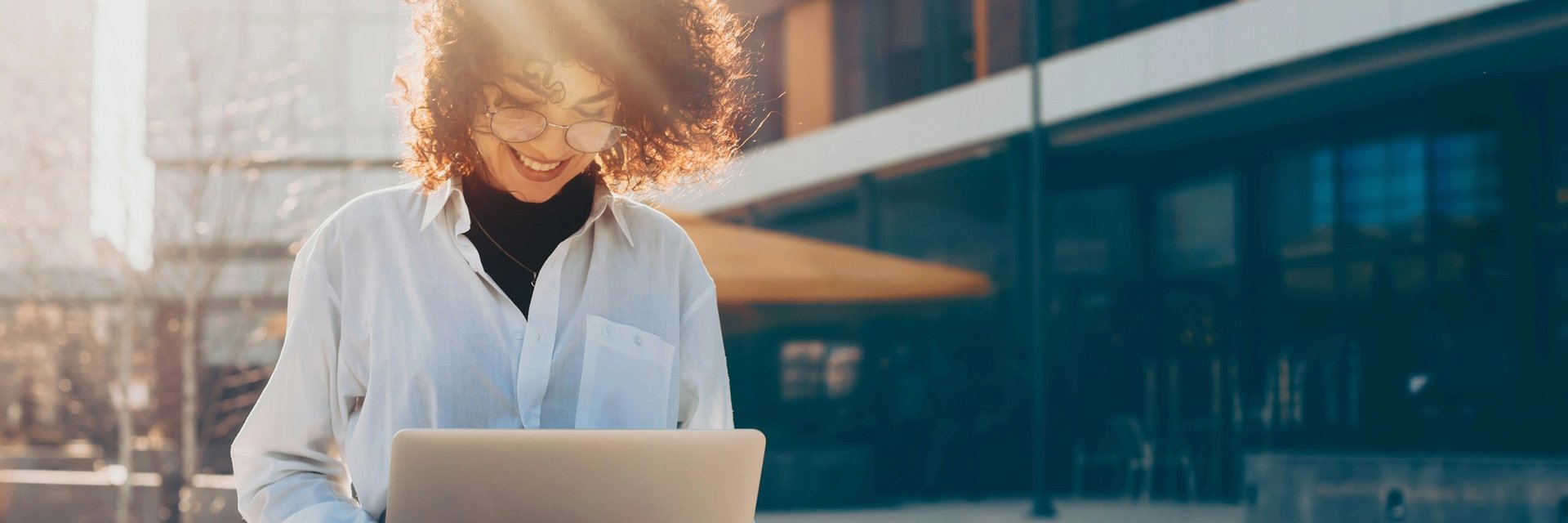 A woman sits outdoors and works on a laptop.