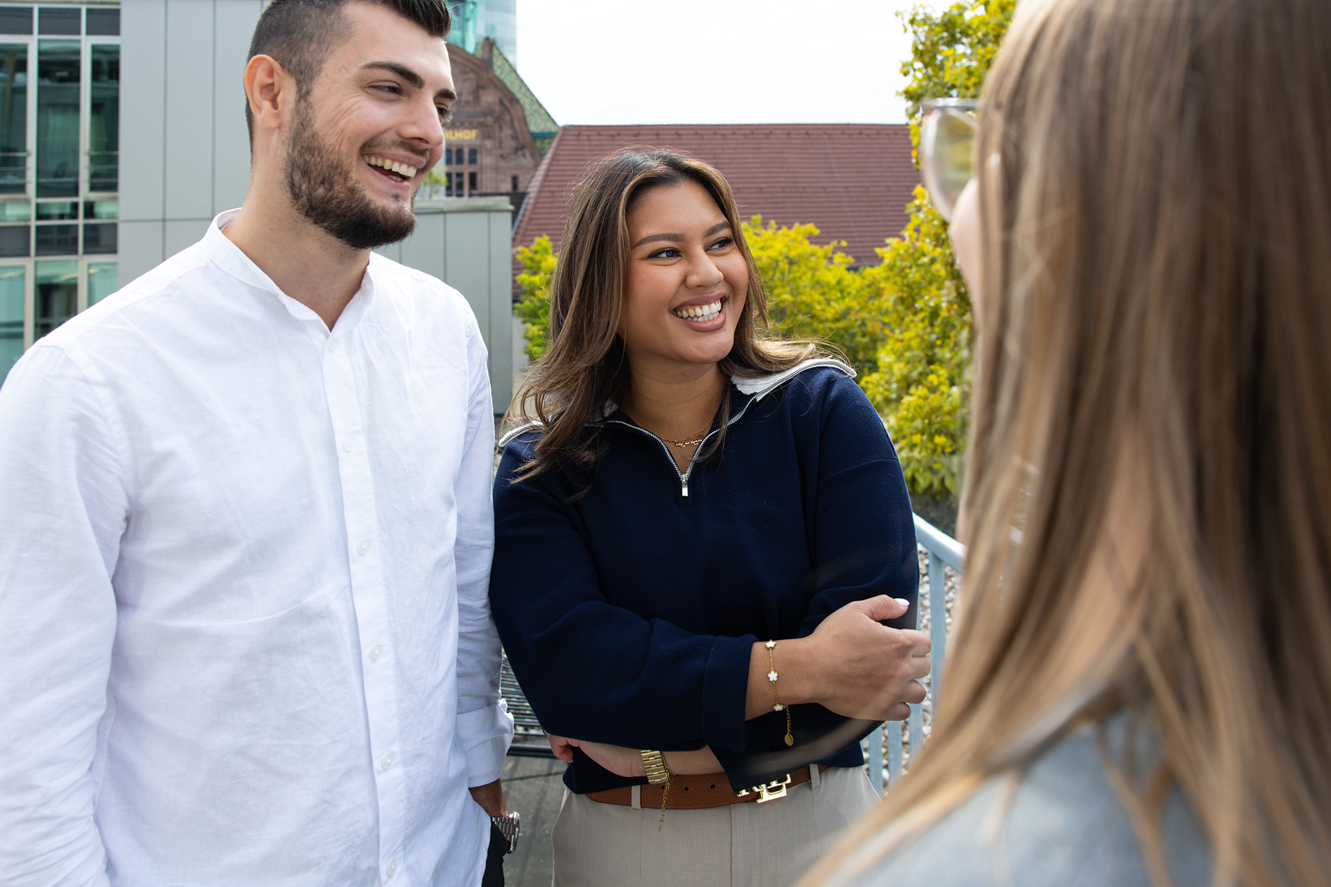 Drei Salesfive Kolleg:innen stehen auf der Terrasse und unterhalten sich.
