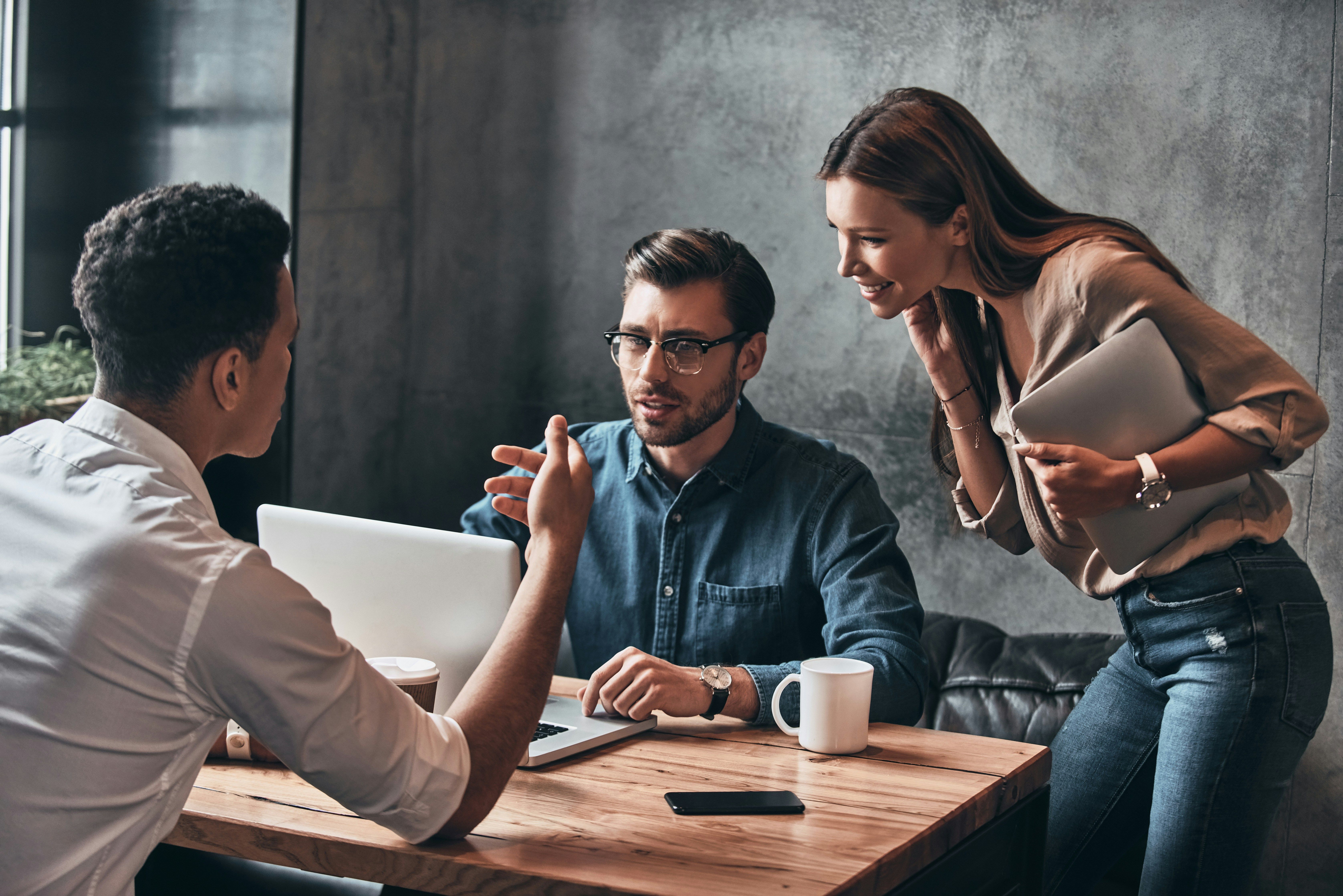 Group of people discussing at laptop