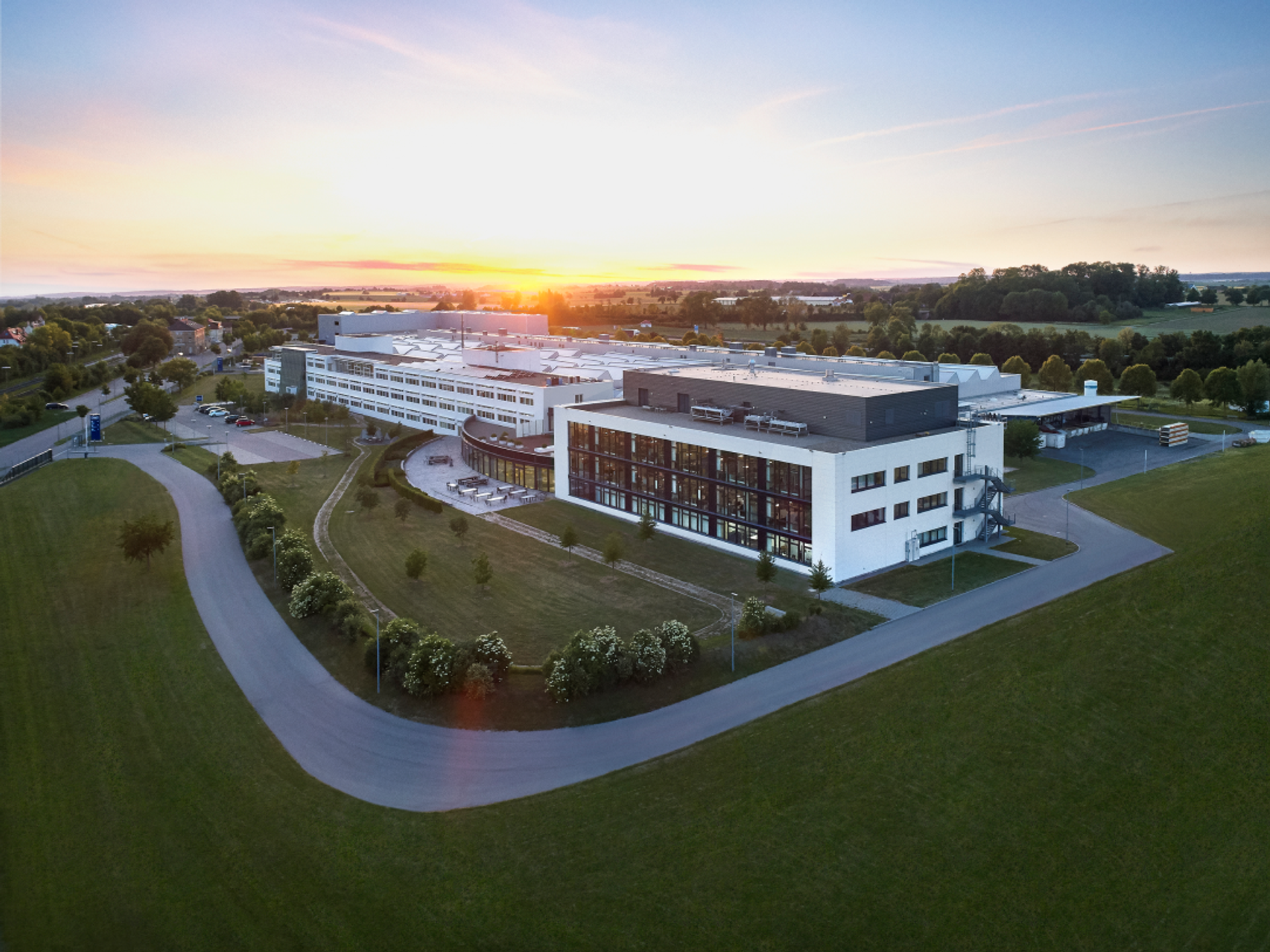 Firmengebäude mit grüner Wiese vor dem Sonnenuntergang.
