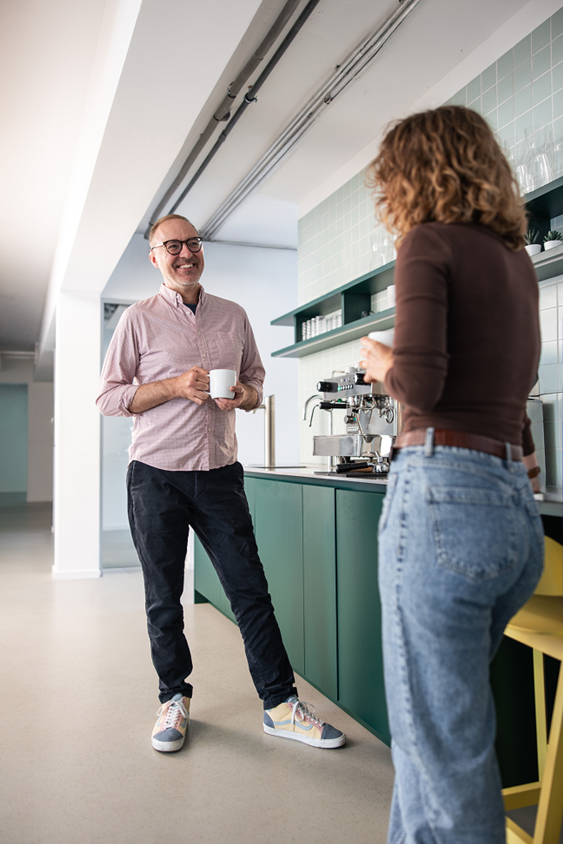 Zwei Salesfive Kolleg:innen stehen in der Kaffeeküche und unterhalten sich. 