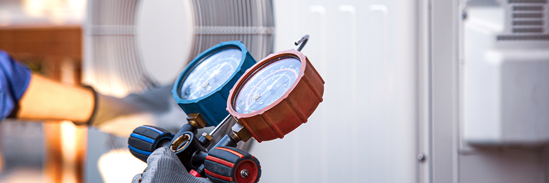 Eine Hand hält ein Messgerät vor einer Wärmepumpe.