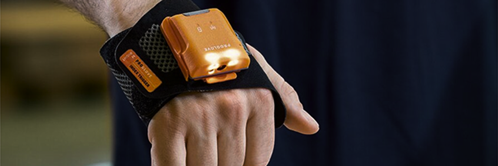 Orangener Scanner ist auf Handrücken angebracht und scannt Strichcode auf Paket.