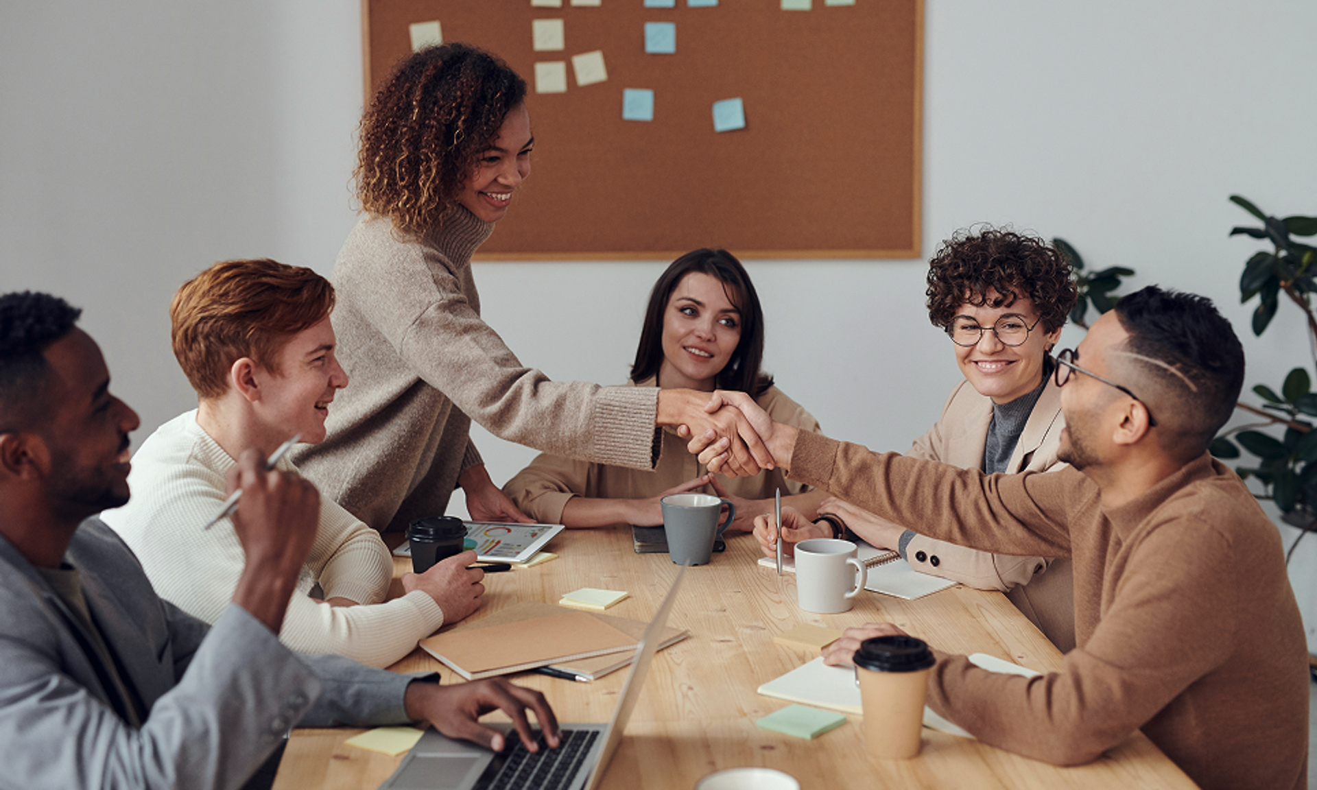 Six people are sitting at the table, two are shaking hands.