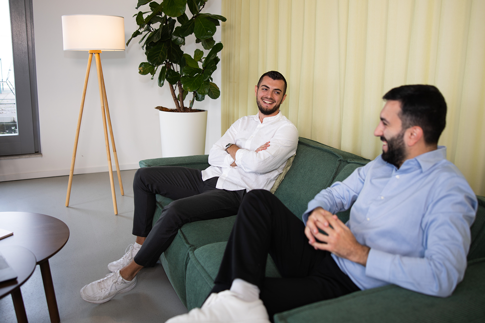 Zwei Salesfive Kollegen sitzen auf einer Couch und unterhalten sich. 