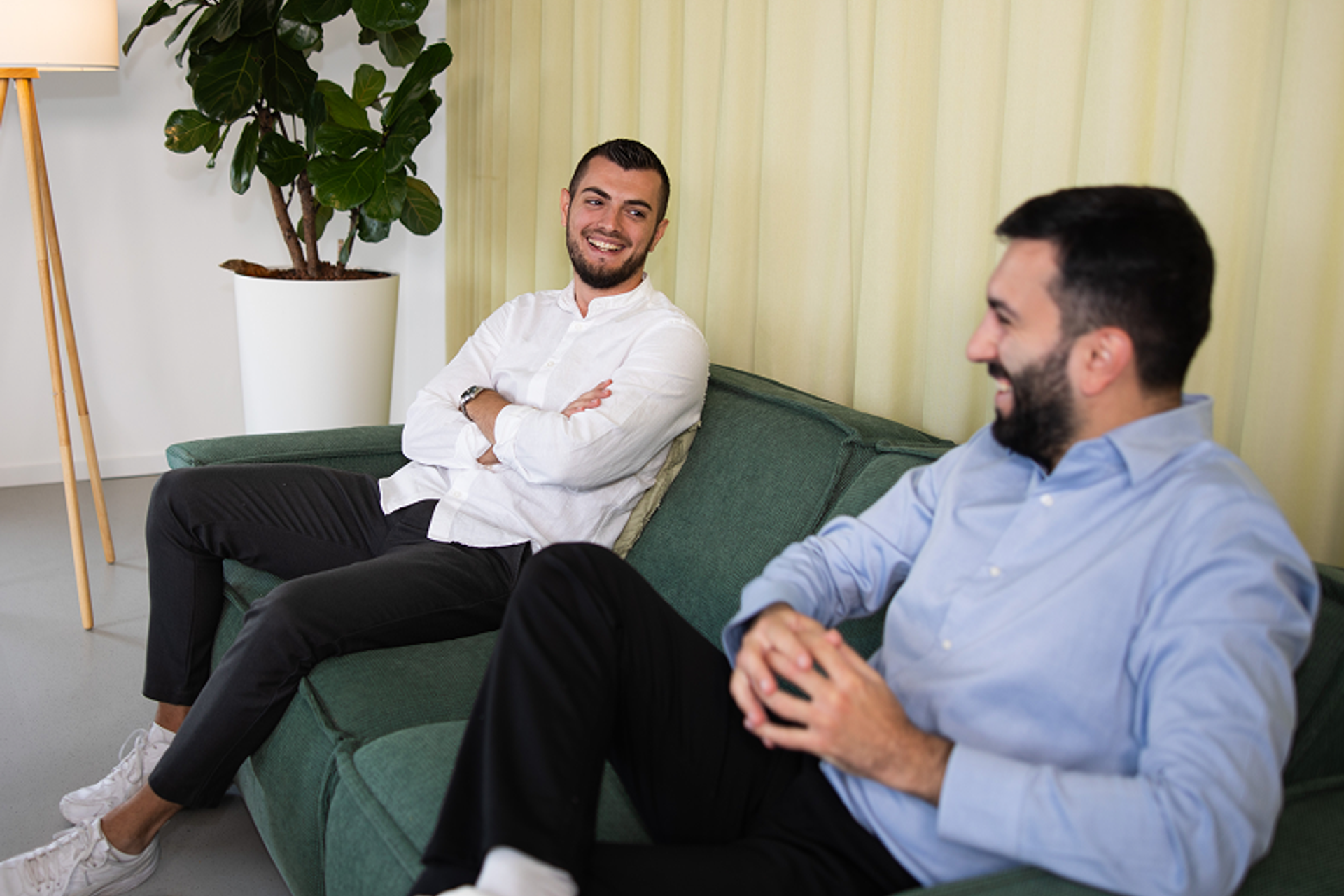 Zwei Salesfive Kollegen sitzen auf einer Couch und unterhalten sich.