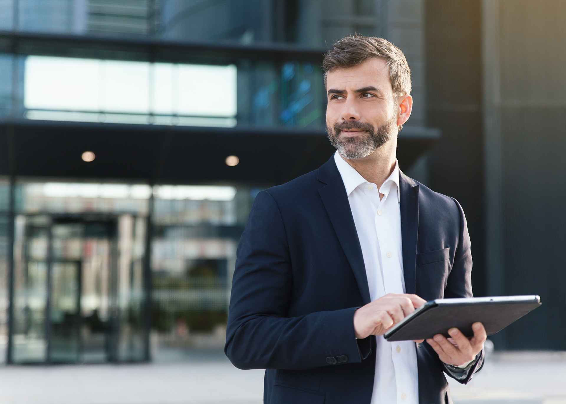 Man stands in front of an office building holding a tablet with Salesforce Agentforce Sales in his hands.
